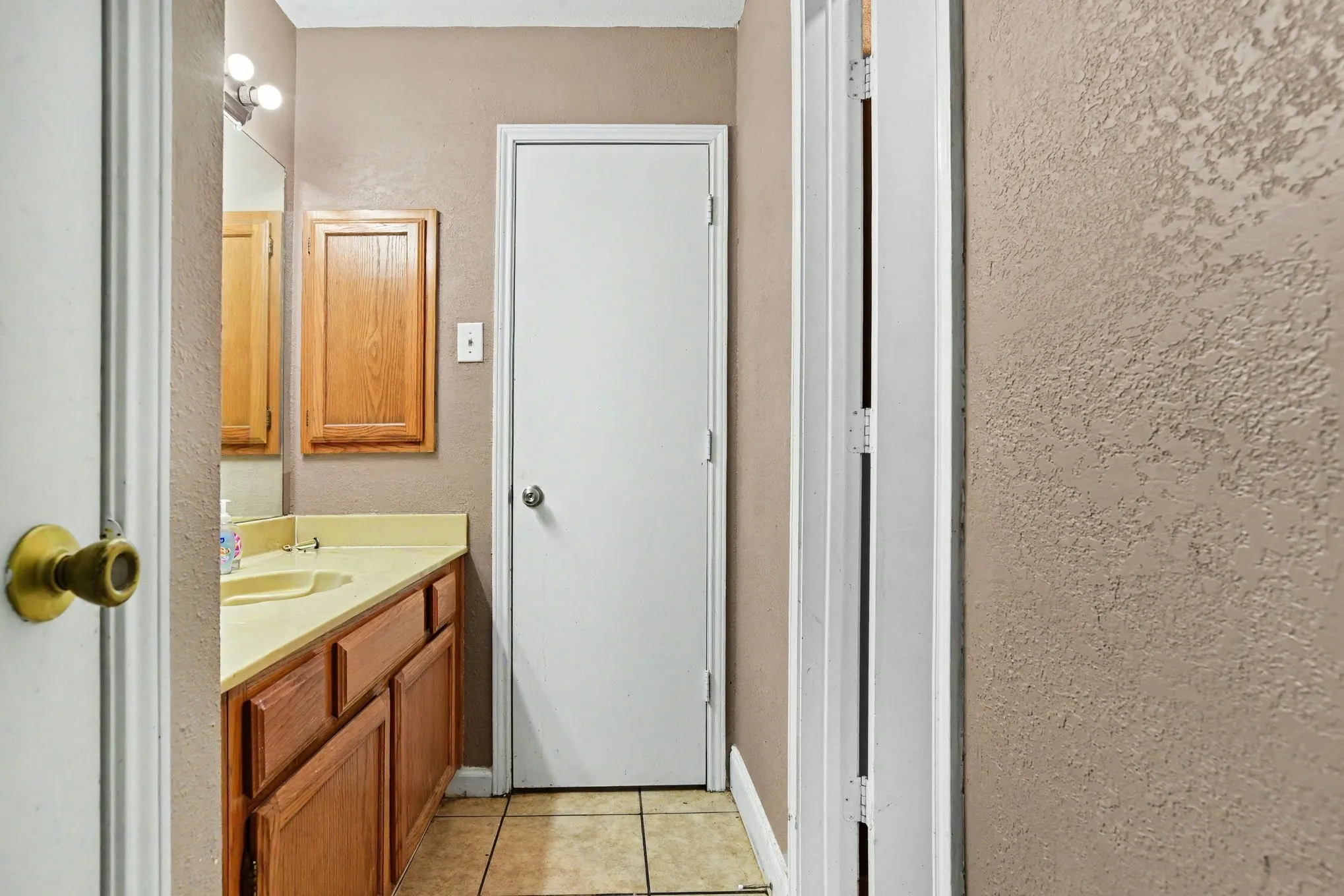 Bathroom hallway perspective displaying vanity storage and doorway access.