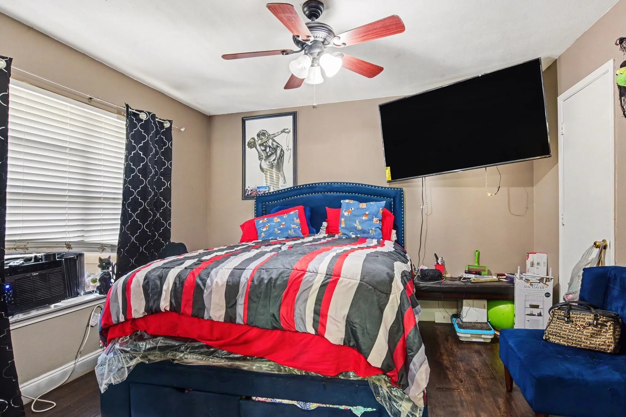 Bedroom alternate view showing large windows with custom blinds and neutral wall decor.