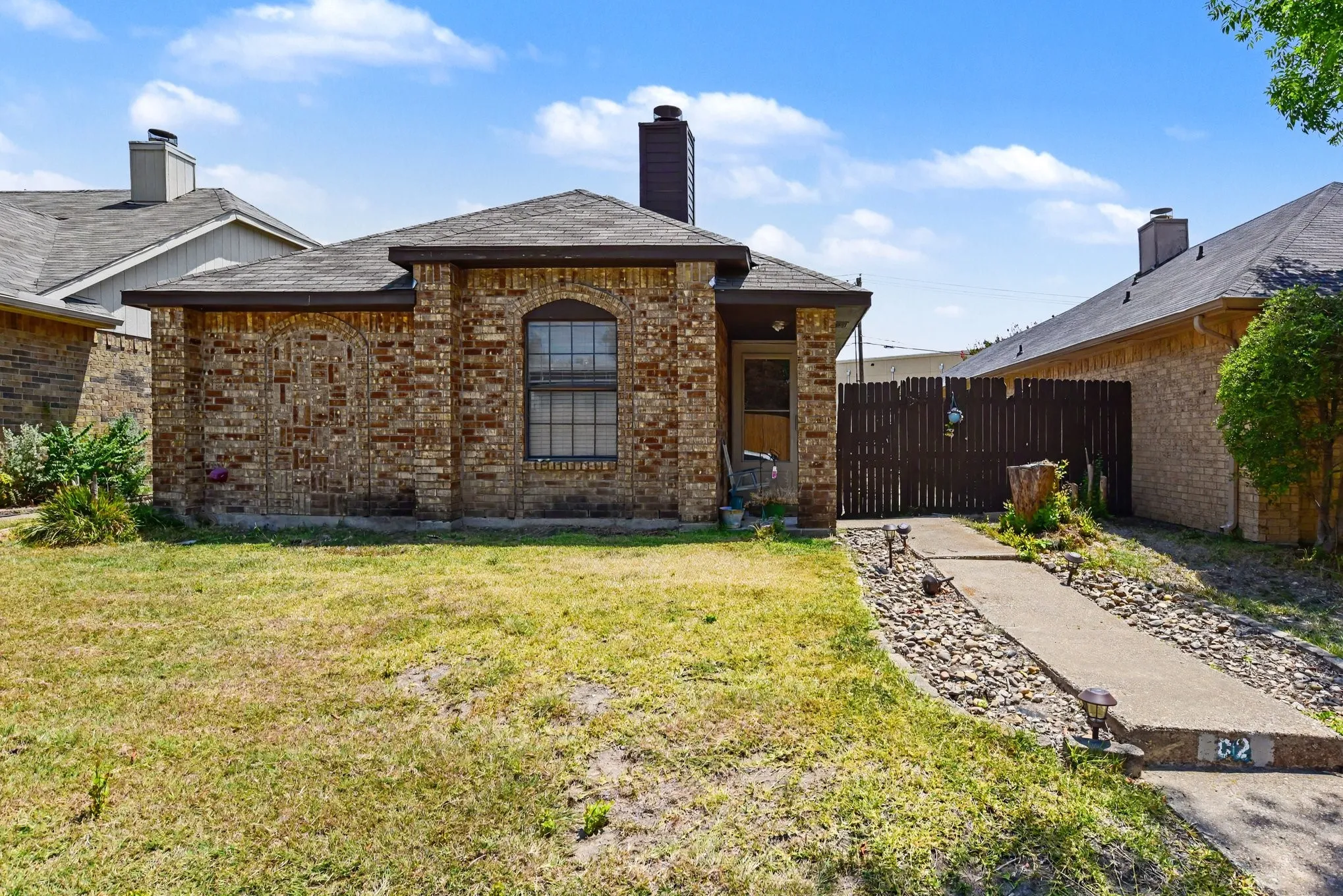 Daytime front view highlighting the classic brick exterior, prominent chimney, and front lawn.