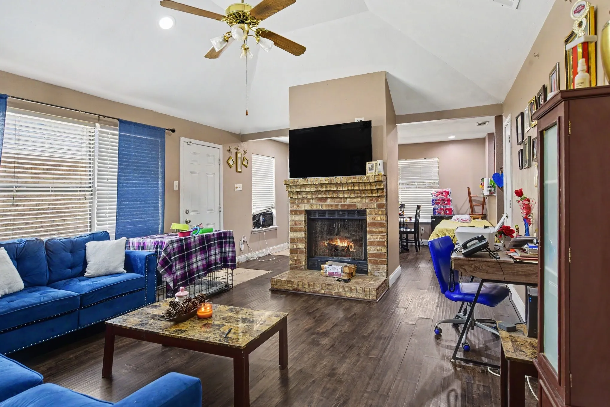 Living room view showcasing plush seating, expansive window layout, and cozy fireplace mantel.