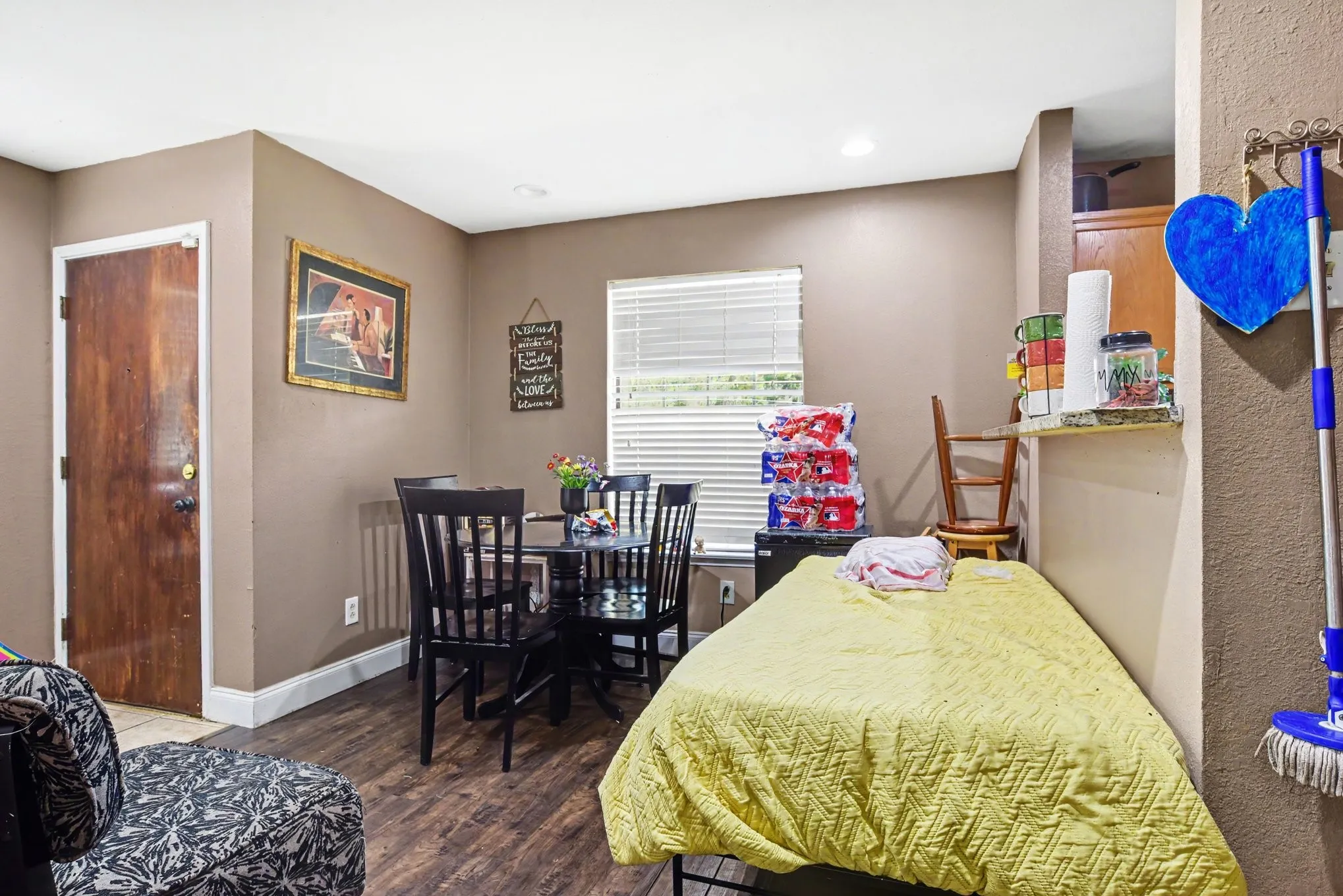 Dining room view displaying light-filled window, dark wood-style flooring, and neutral wall tones.