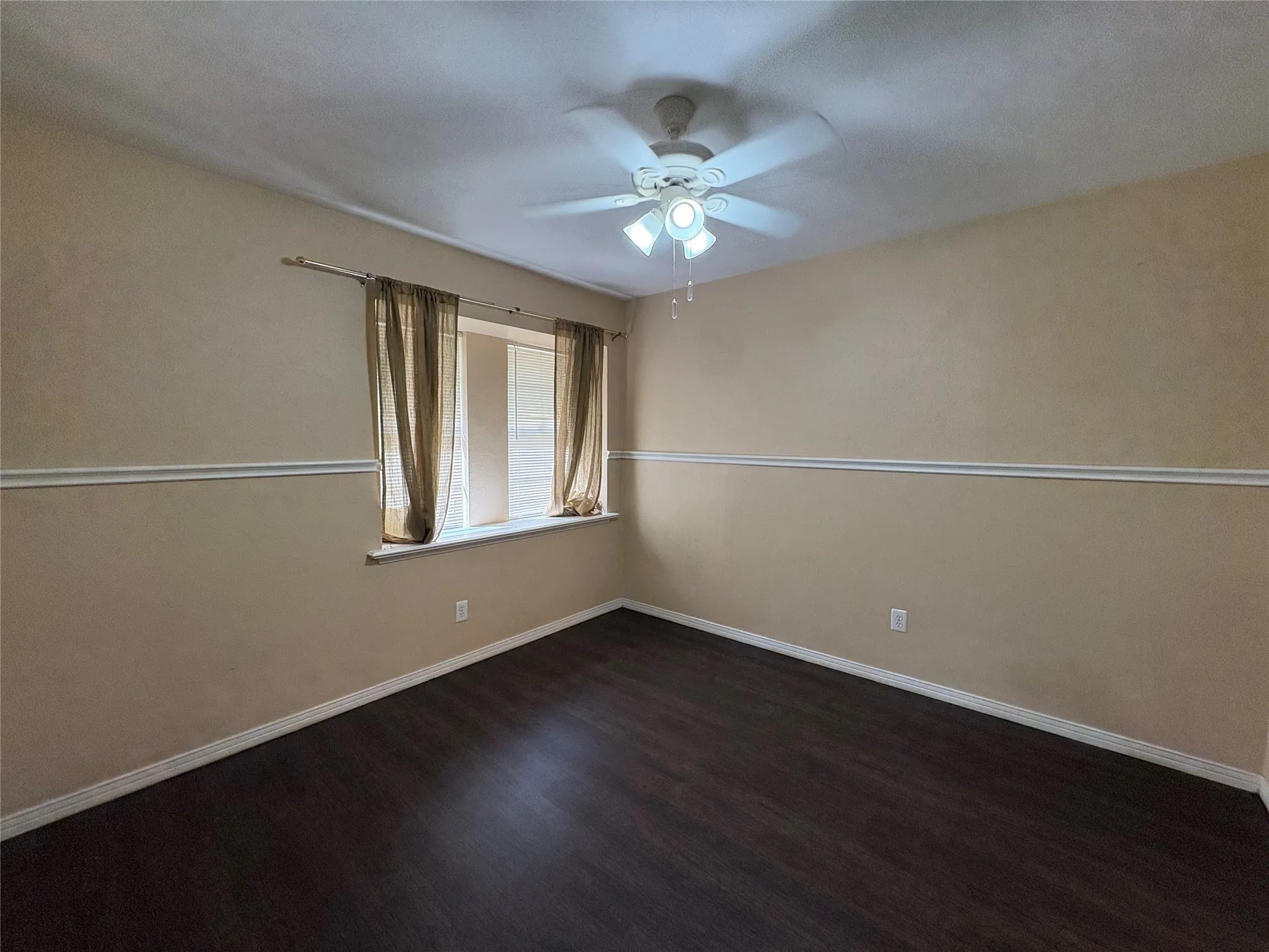 Wood-finish flooring, ceiling fan with integrated lighting, window with a sill, and decorative chair rail molding