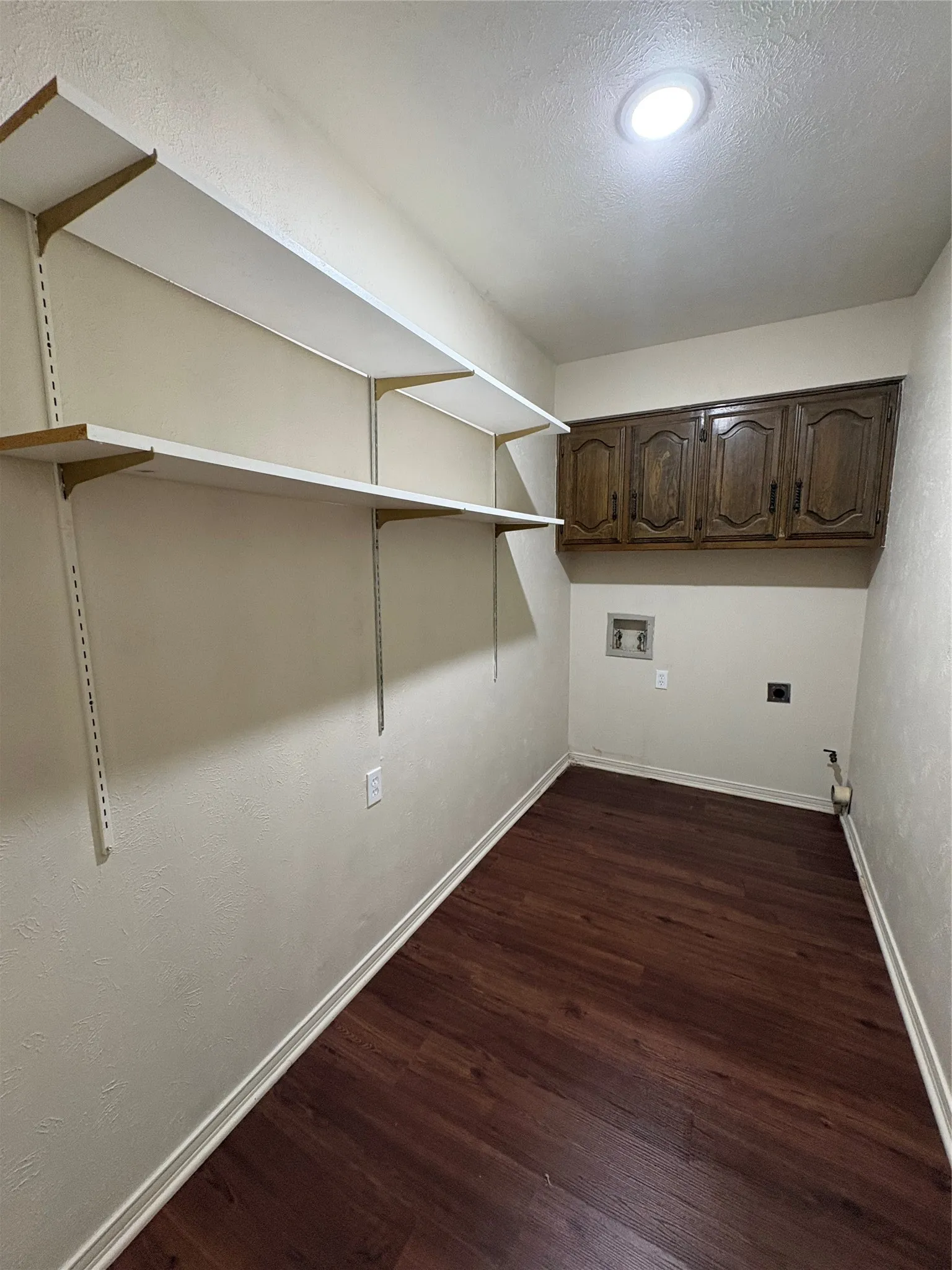 Wood-finish flooring with built-in shelving, overhead cabinetry, and recessed lighting