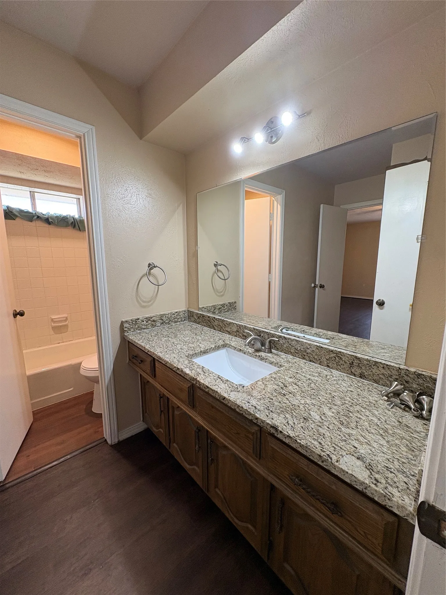 Extended vanity with a rectangular undermount sink, granite-style countertop, and wood-finish cabinetry
