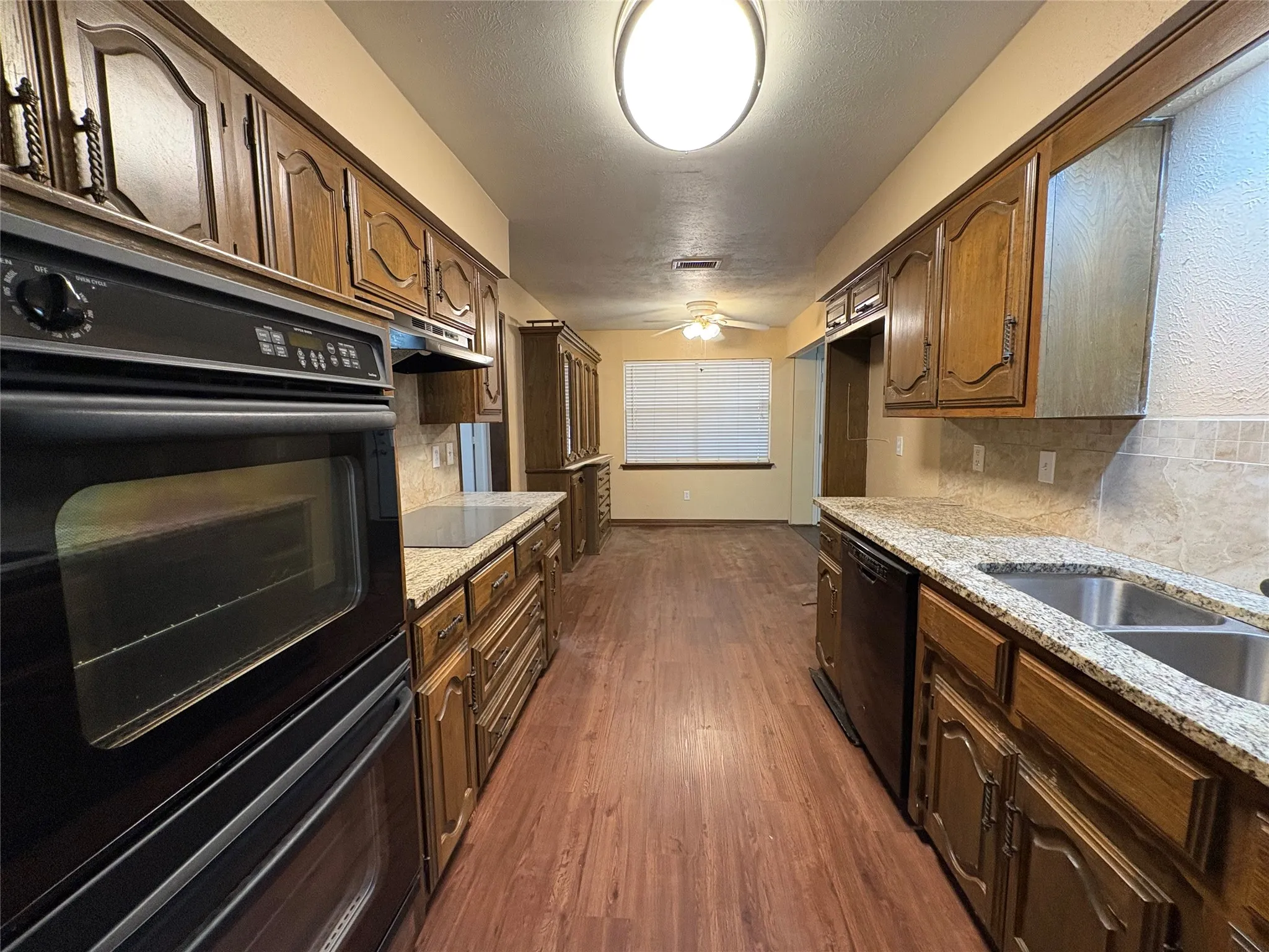Galley kitchen featuring wood cabinetry, integrated double oven, and a built-in cooktop