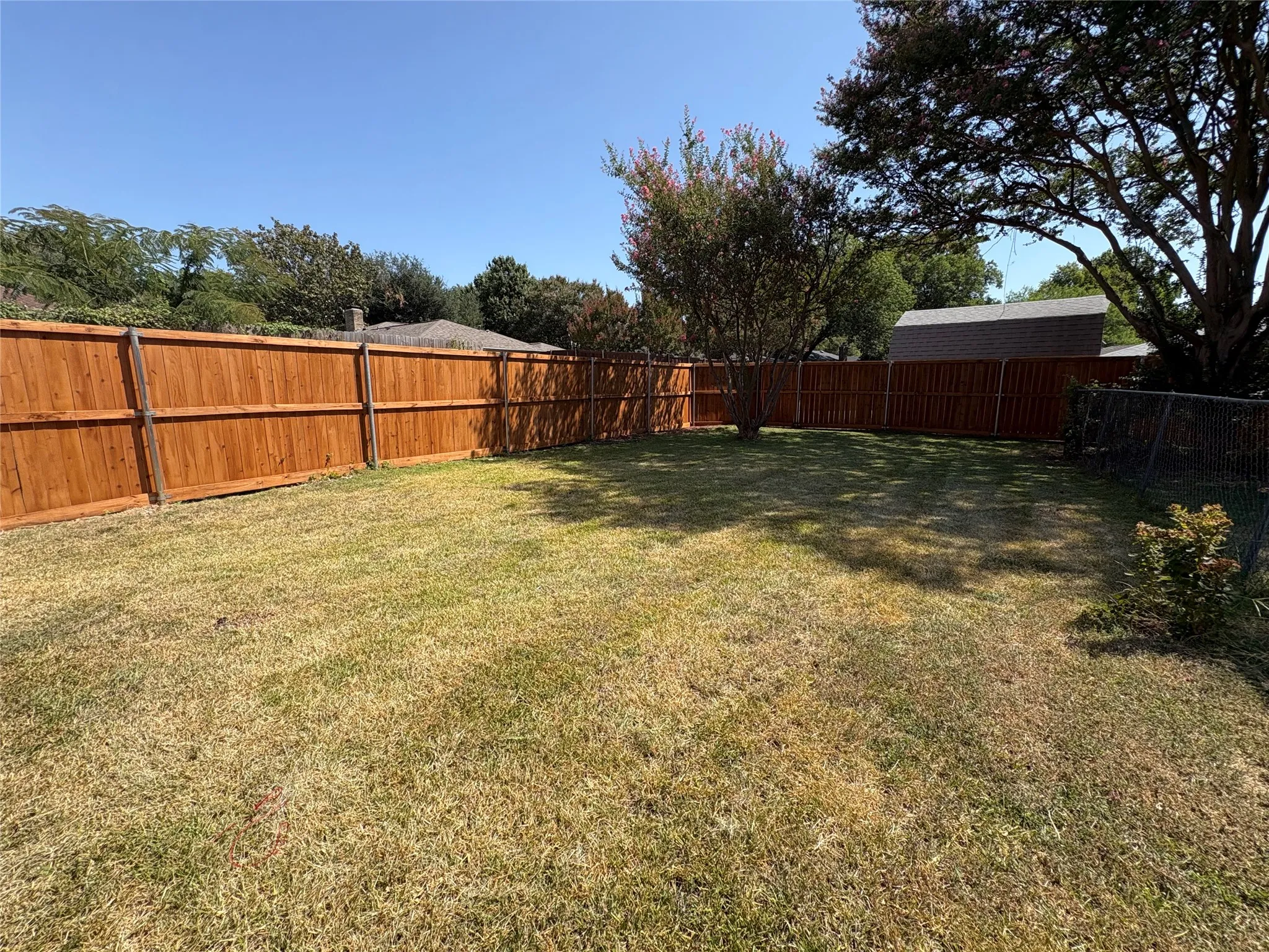 Spacious backyard featuring wood fencing and established trees