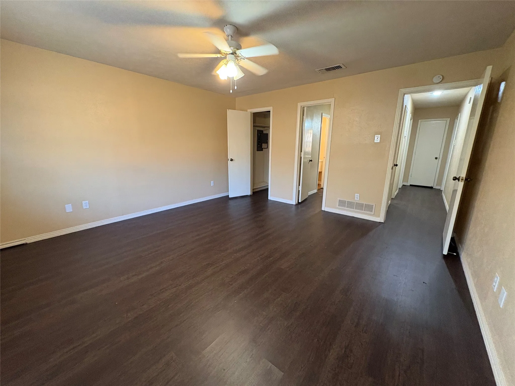 Spacious room featuring wood-finish flooring, neutral-toned walls, and a ceiling fan