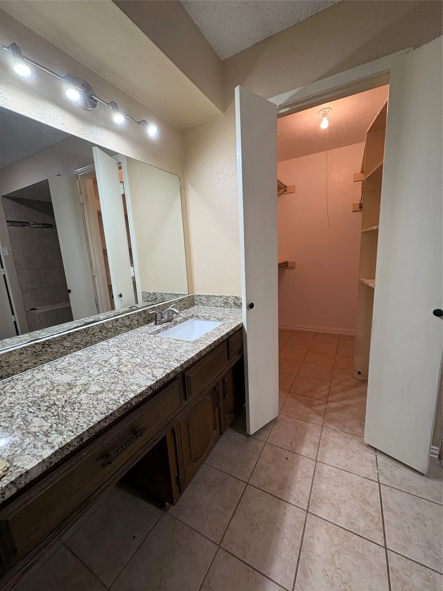 Spacious vanity with a granite countertop, undermount sink, and wood-finish cabinetry