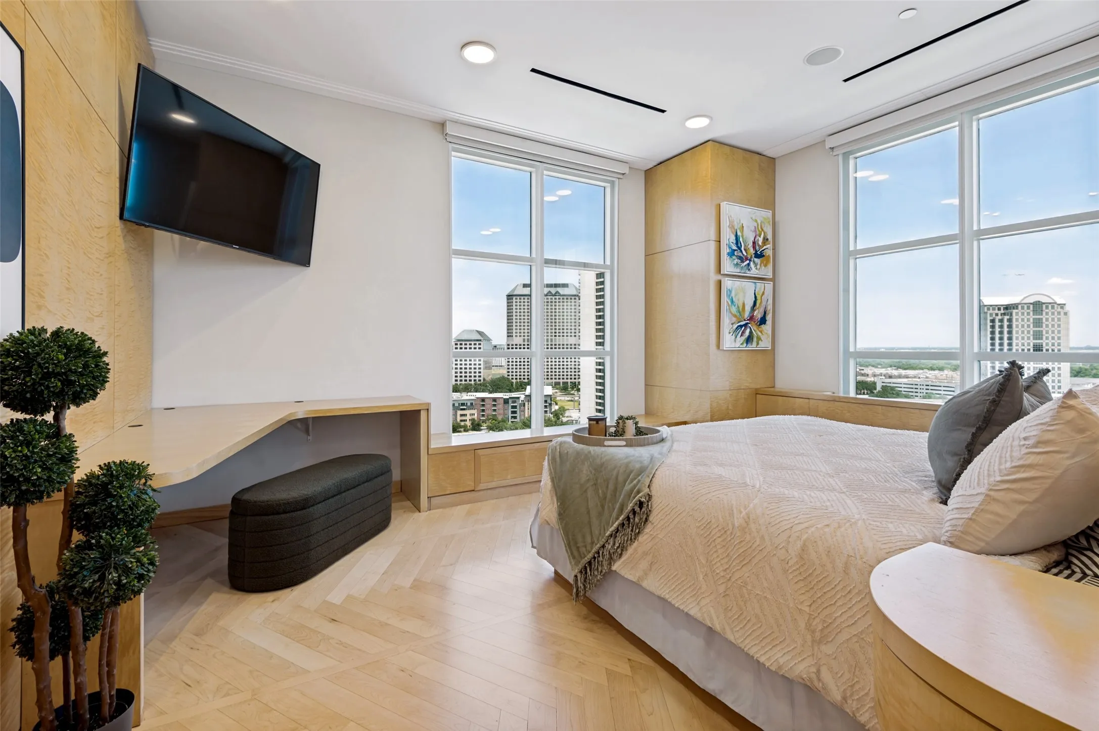 Expansive windows, light wood-finish flooring in a herringbone pattern, recessed lighting, built-in desk, and integrated wood paneling