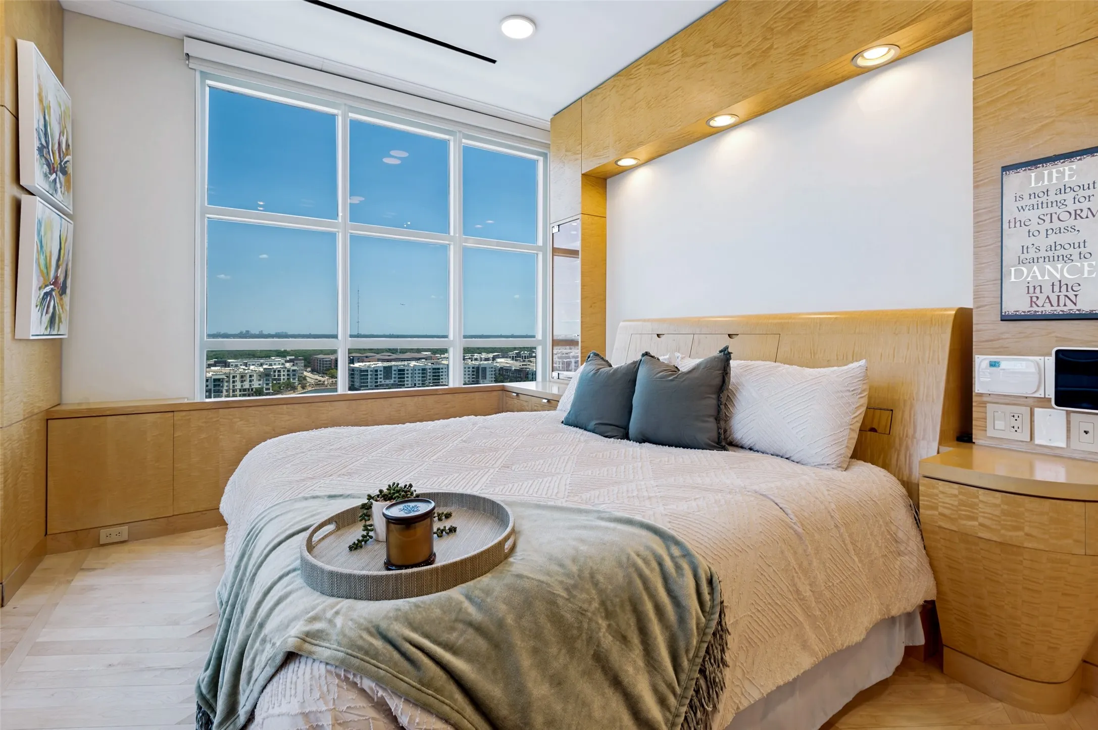 Expansive multi-pane window, built-in blonde wood-finish cabinetry, recessed ceiling lighting, and wood-finish flooring