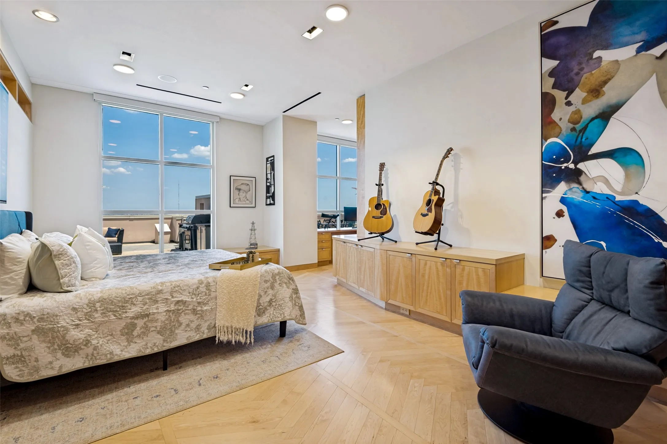 Expansive windows, light wood-finish flooring, recessed lighting, built-in wood-finish cabinetry, and a private balcony