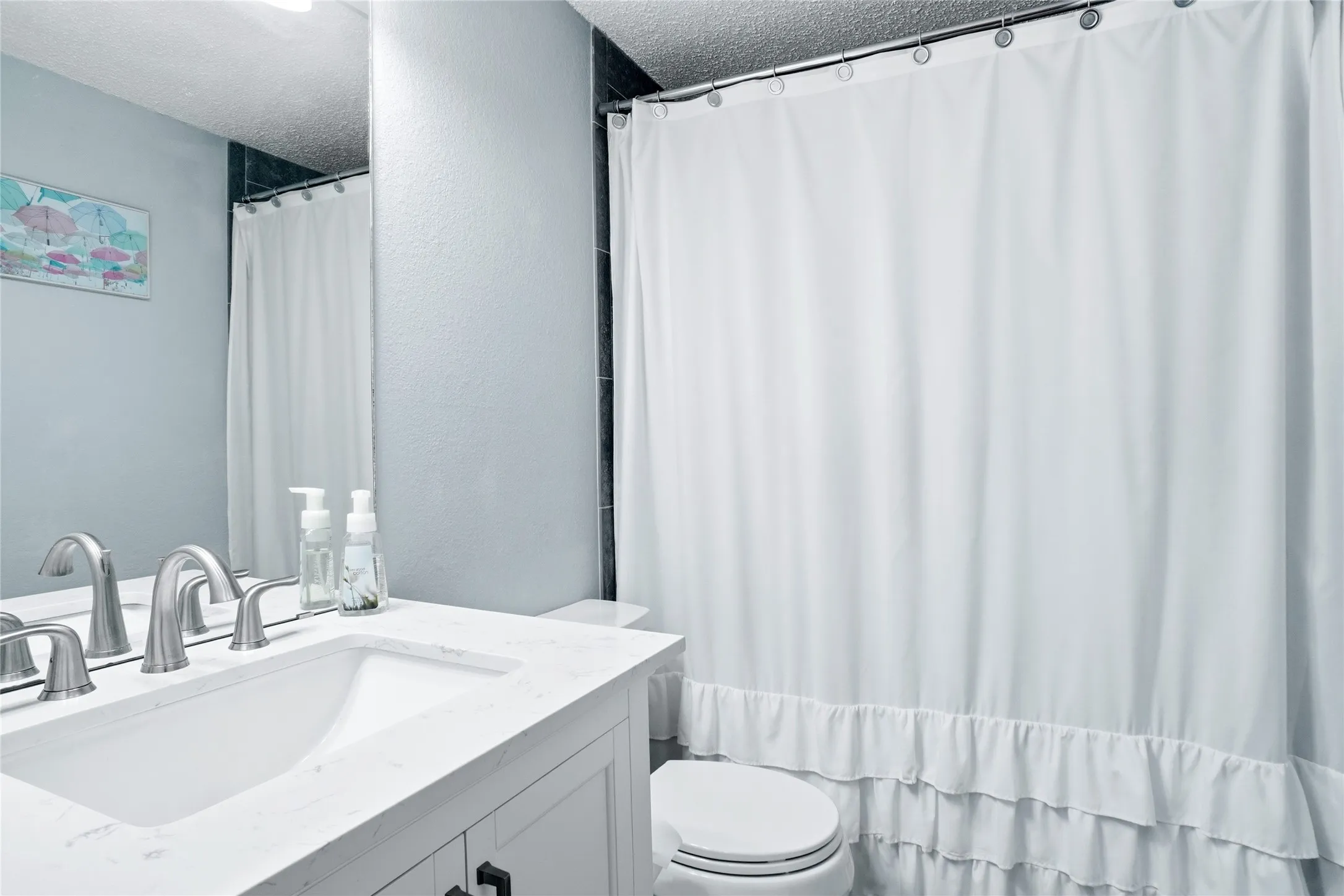 White vanity with a single basin sink and brushed nickel faucet fixtures