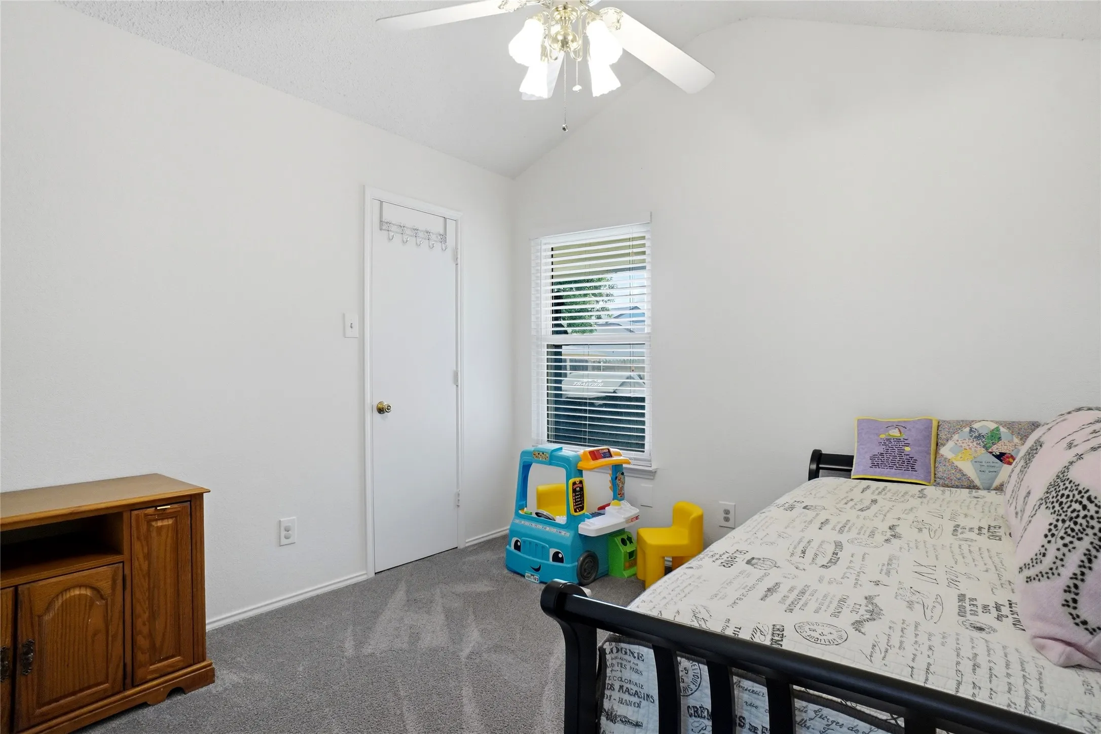 Vaulted ceiling with a ceiling fan, white walls, gray carpet, and a window with blinds