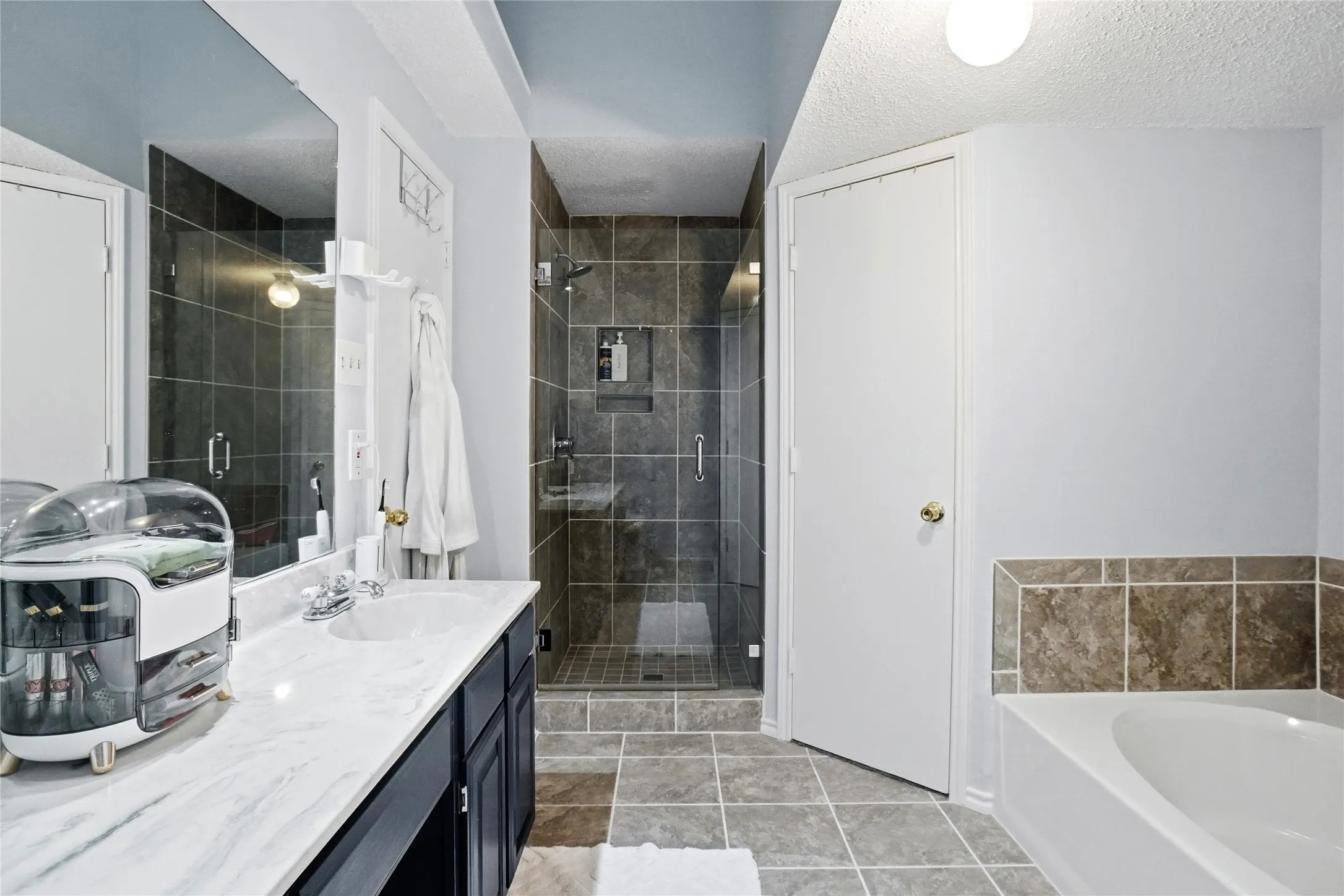 Glass-enclosed shower with tile surround, built-in shelf, and chrome fixtures