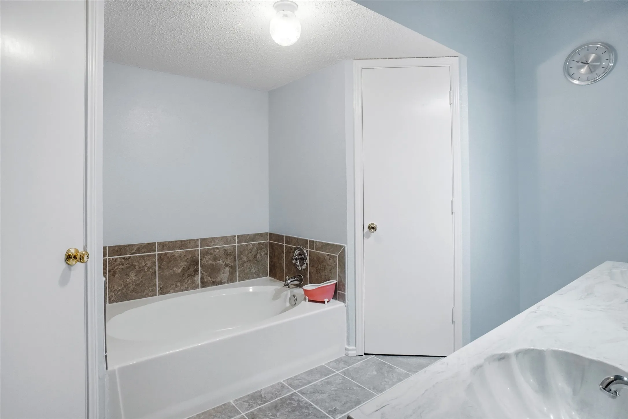 Bathtub with tile surround, tile flooring, and a vanity with an integrated sink