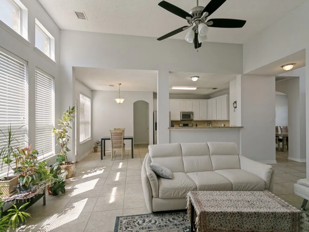 Vaulted ceilings, a contemporary ceiling fan, and abundant natural light from multiple windows