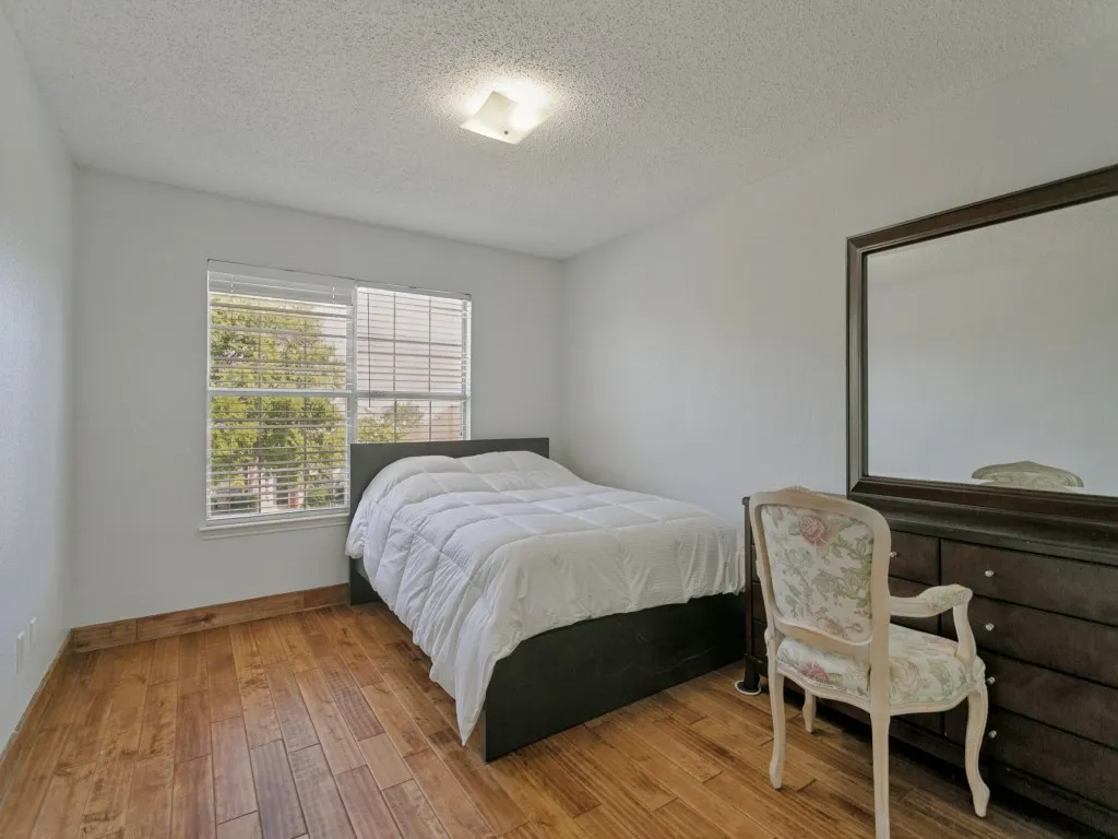 Wood-finish flooring, white walls, window with blinds, and a ceiling-mounted light fixture