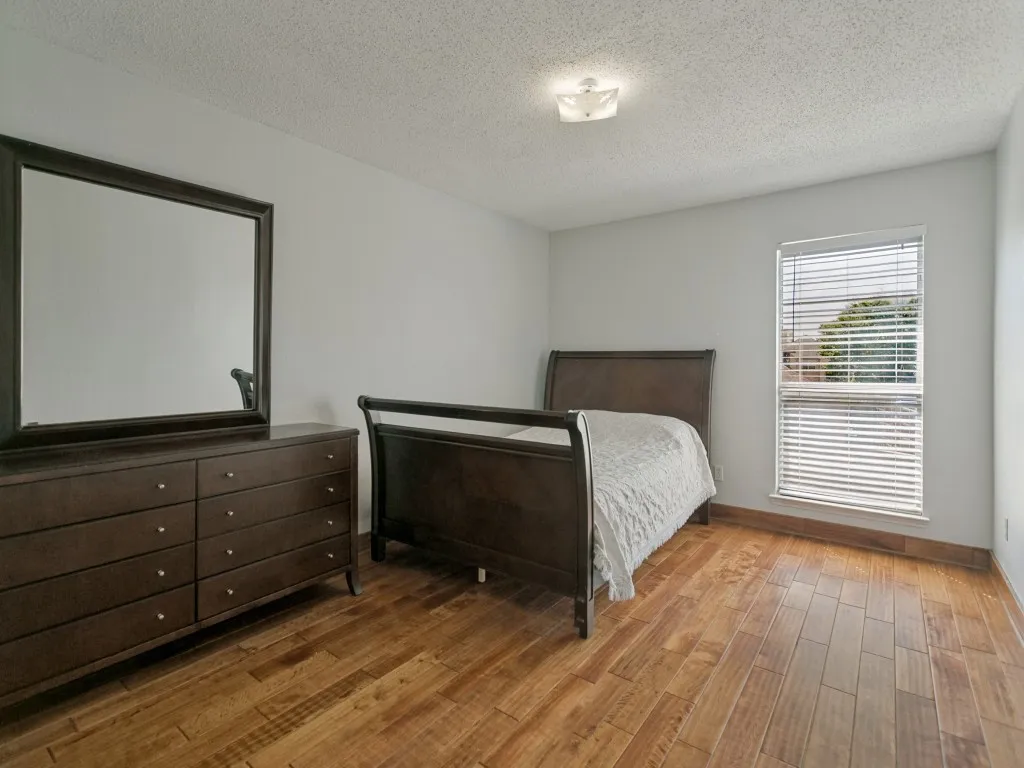 Hardwood flooring, window with blinds, overhead light fixture, light gray wall paint