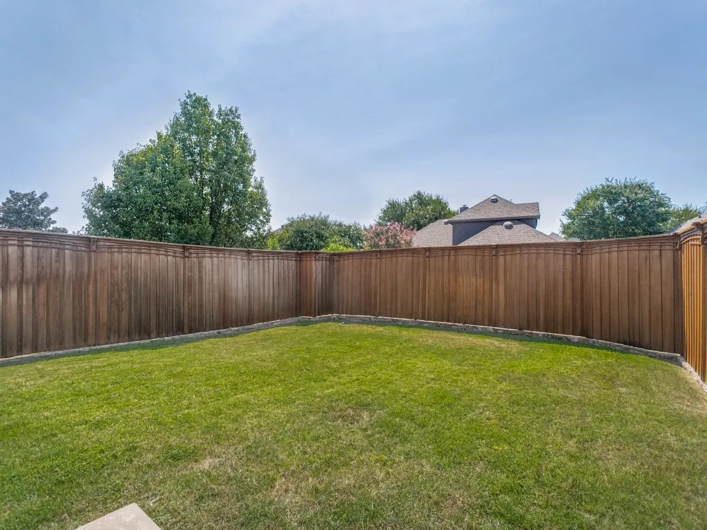 Expansive green lawn enclosed by a wood privacy fence