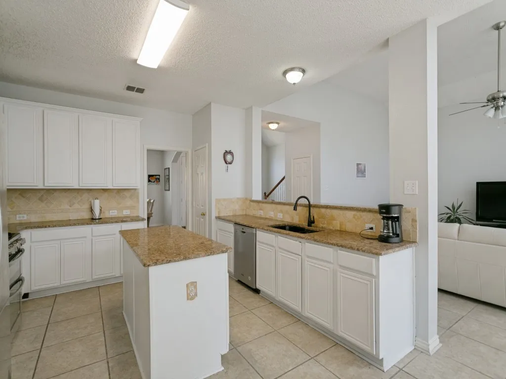 Kitchen featuring white cabinetry, granite countertops, tile flooring, a center island, and stainless steel appliances