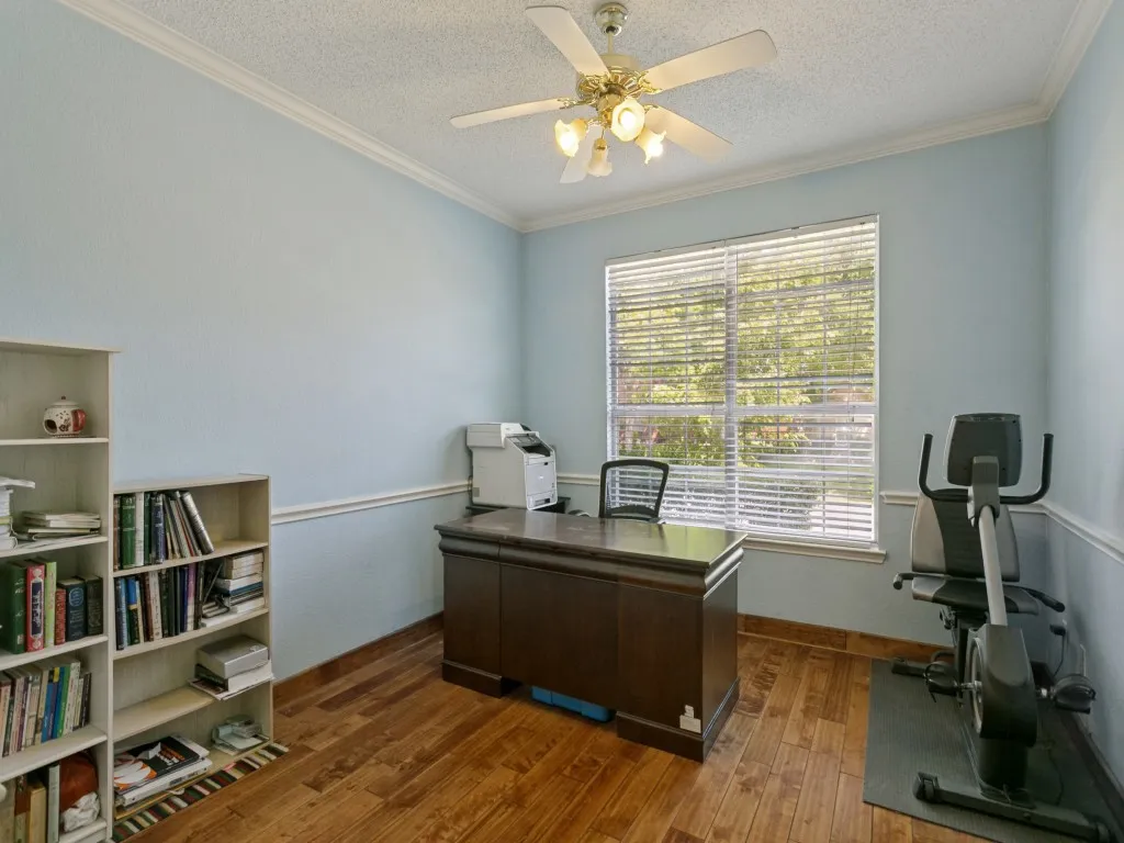 Bright room featuring wood-finish flooring, a ceiling fan with integrated lighting, and a window with blinds