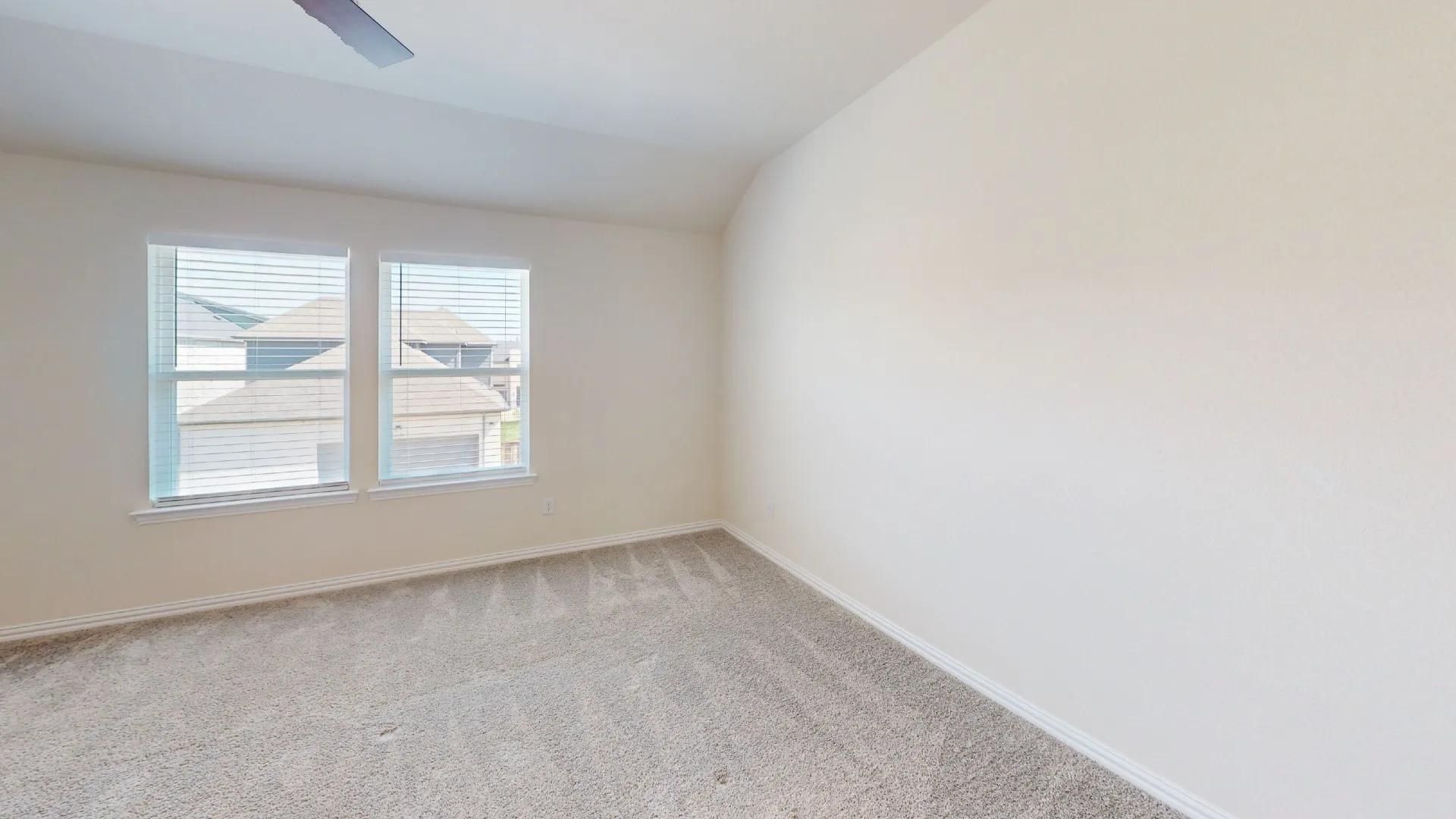 Neutral-toned wall finishes, dual window installation with blinds, and textured carpet flooring