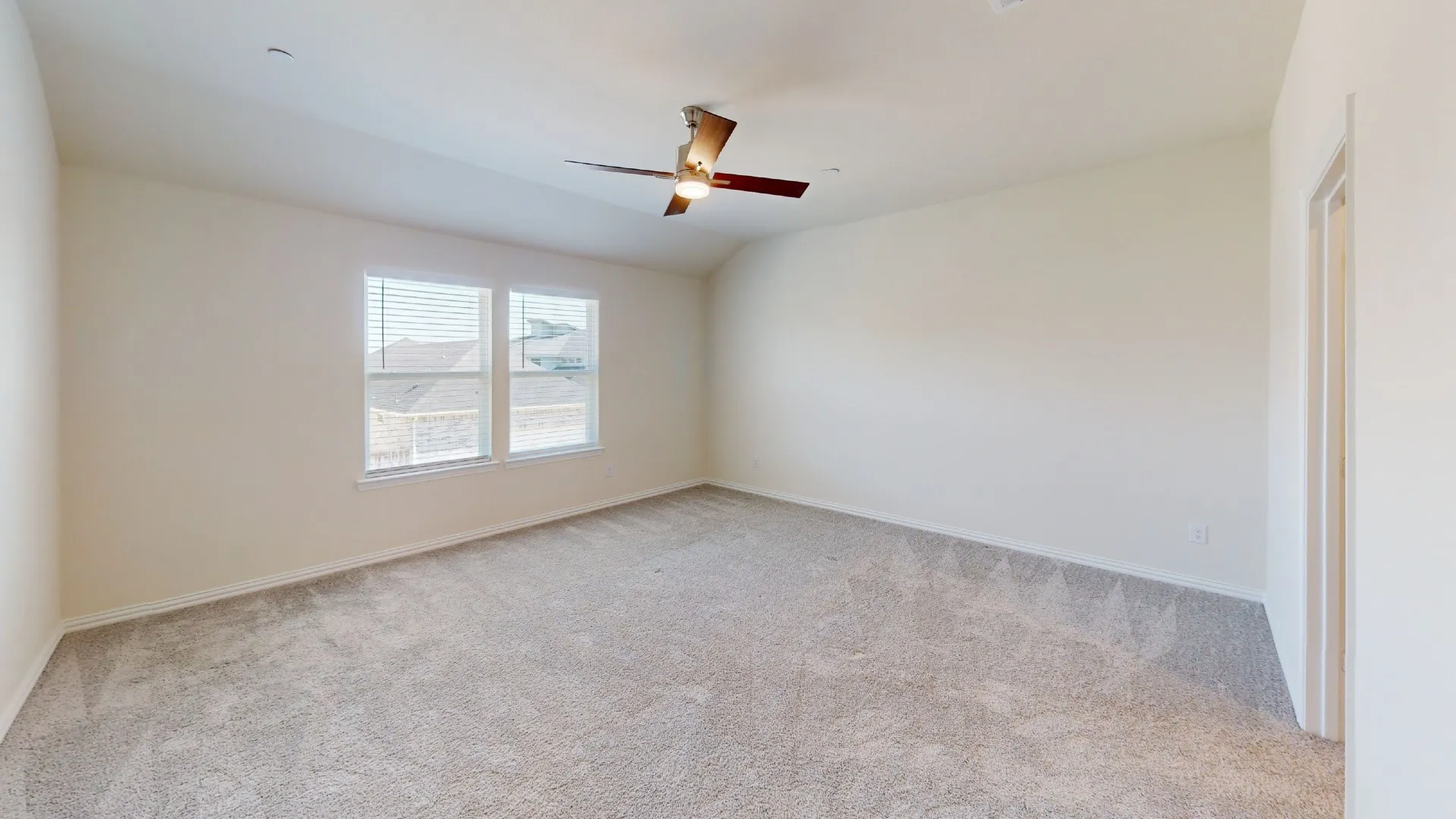Carpeted room featuring multiple windows, a ceiling fan with integrated lighting, and a neutral color palette