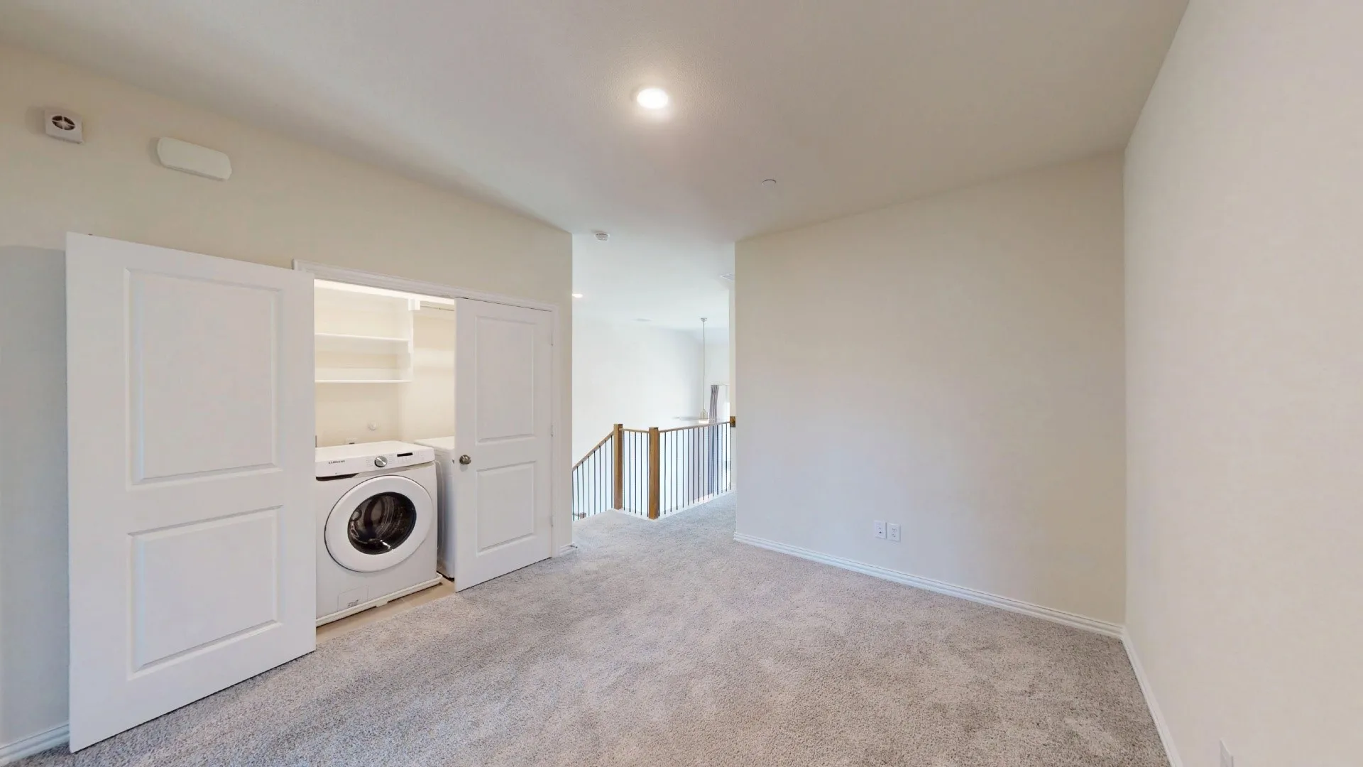 Laundry closet with built-in shelving, white paneled doors, light gray carpet, and recessed ceiling lighting
