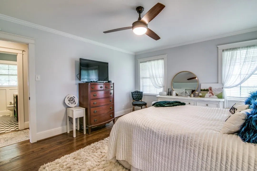 Hardwood flooring, crown molding, a ceiling fan with integrated lighting, and two windows with blinds