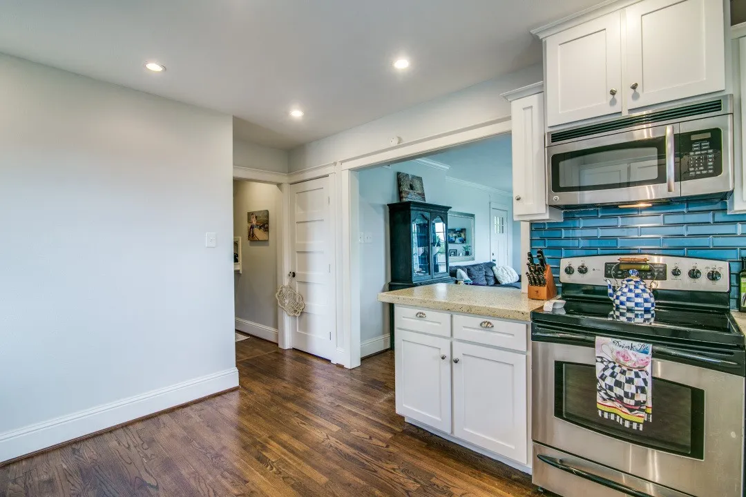 Stainless steel range with a coordinating microwave, white shaker-style cabinetry, and a blue subway tile backsplash