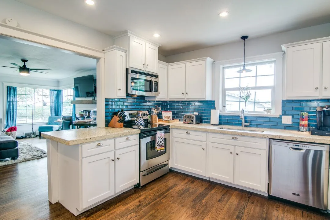 White cabinetry with a blue subway tile backsplash and stainless steel appliances