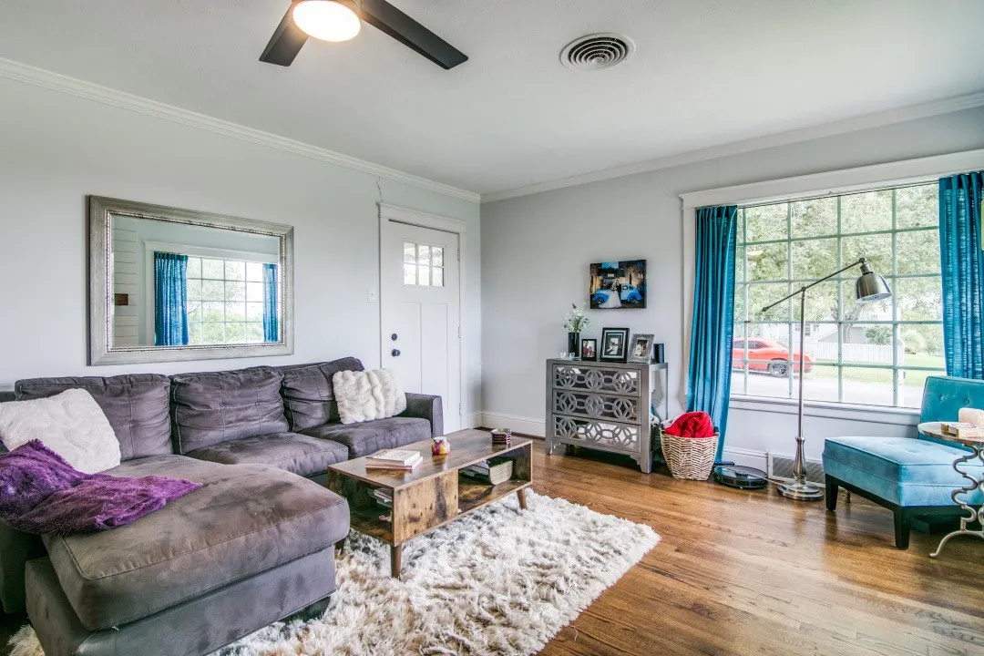 Hardwood-finish flooring, a ceiling fan with integrated lighting, crown molding, and a multi-pane window with white trim