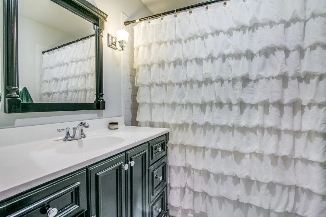 Bathroom vanity featuring a single basin, a chrome faucet, and dark-finished cabinetry with decorative hardware