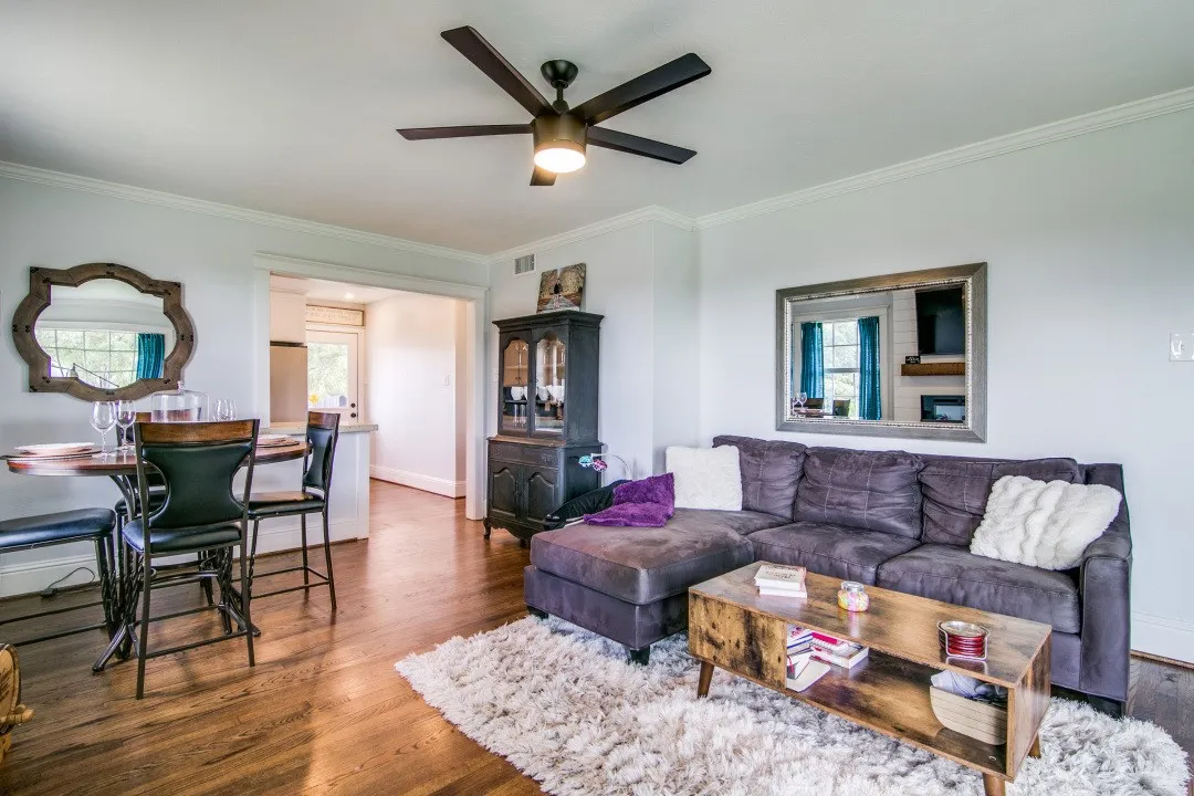 Hardwood-style flooring throughout, crown molding, ceiling fan with integrated lighting, and an open doorway leading to an additional space
