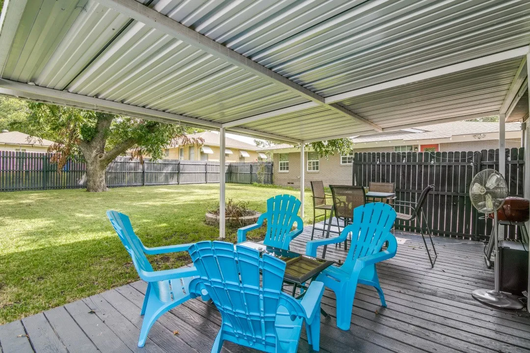 Expansive backyard featuring a manicured lawn, full privacy fencing, and a large mature tree