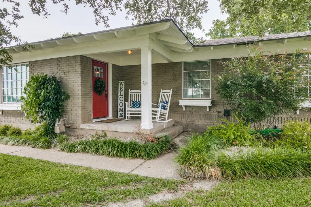 Brick exterior with a covered porch, white columns, and a red entry door
