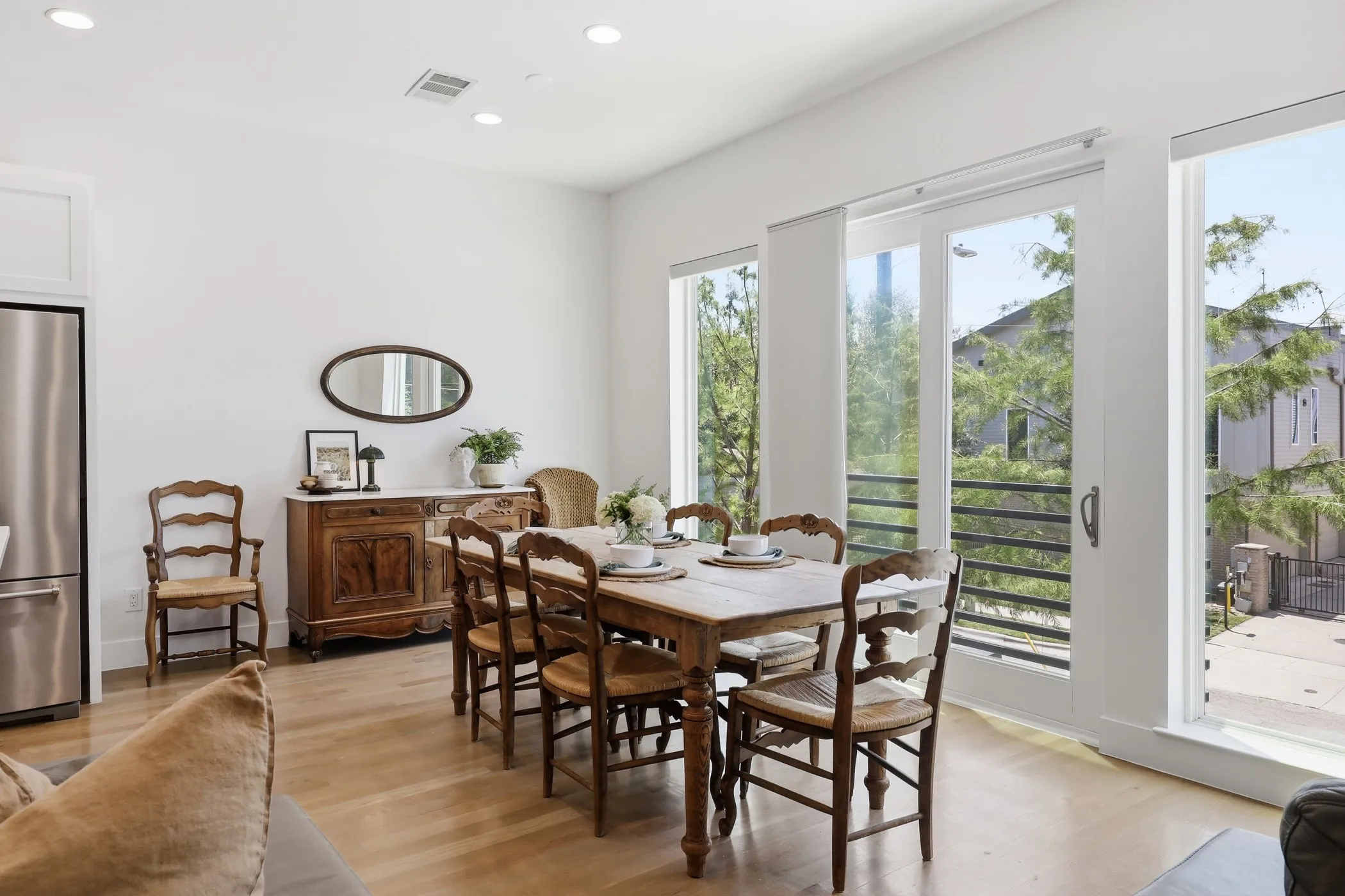 Recessed lighting, light wood-finish flooring, stainless steel refrigerator, and glass sliding doors with a balcony
