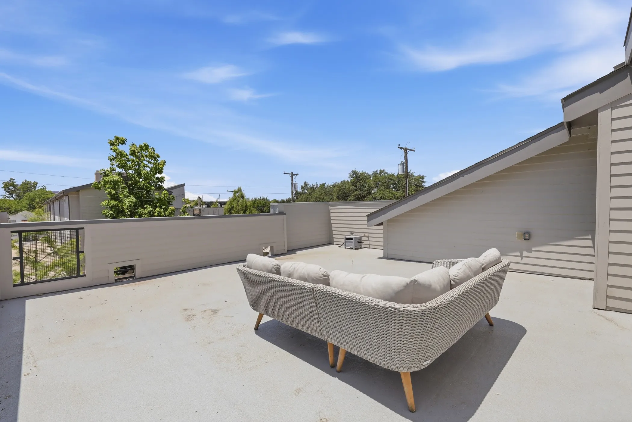 Expansive rooftop patio featuring a neutral concrete surface and partial privacy wall