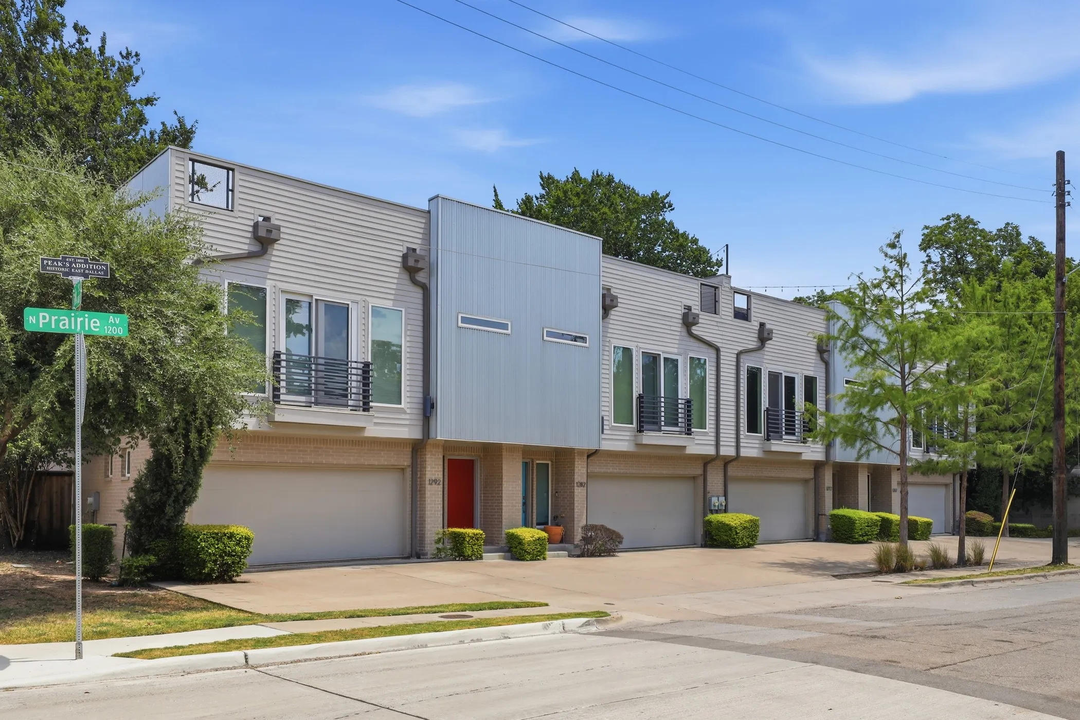 Modern townhome exterior featuring an attached garage, large windows, and a balcony with metal railings