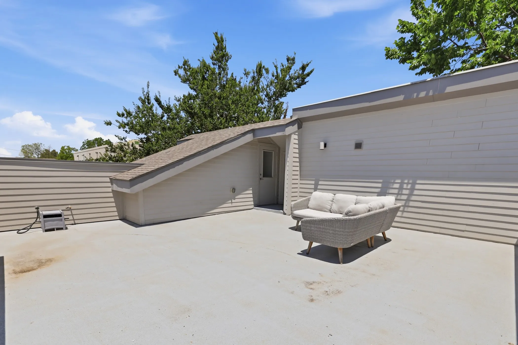 Outdoor patio with light-colored flooring and a sloped roof structure