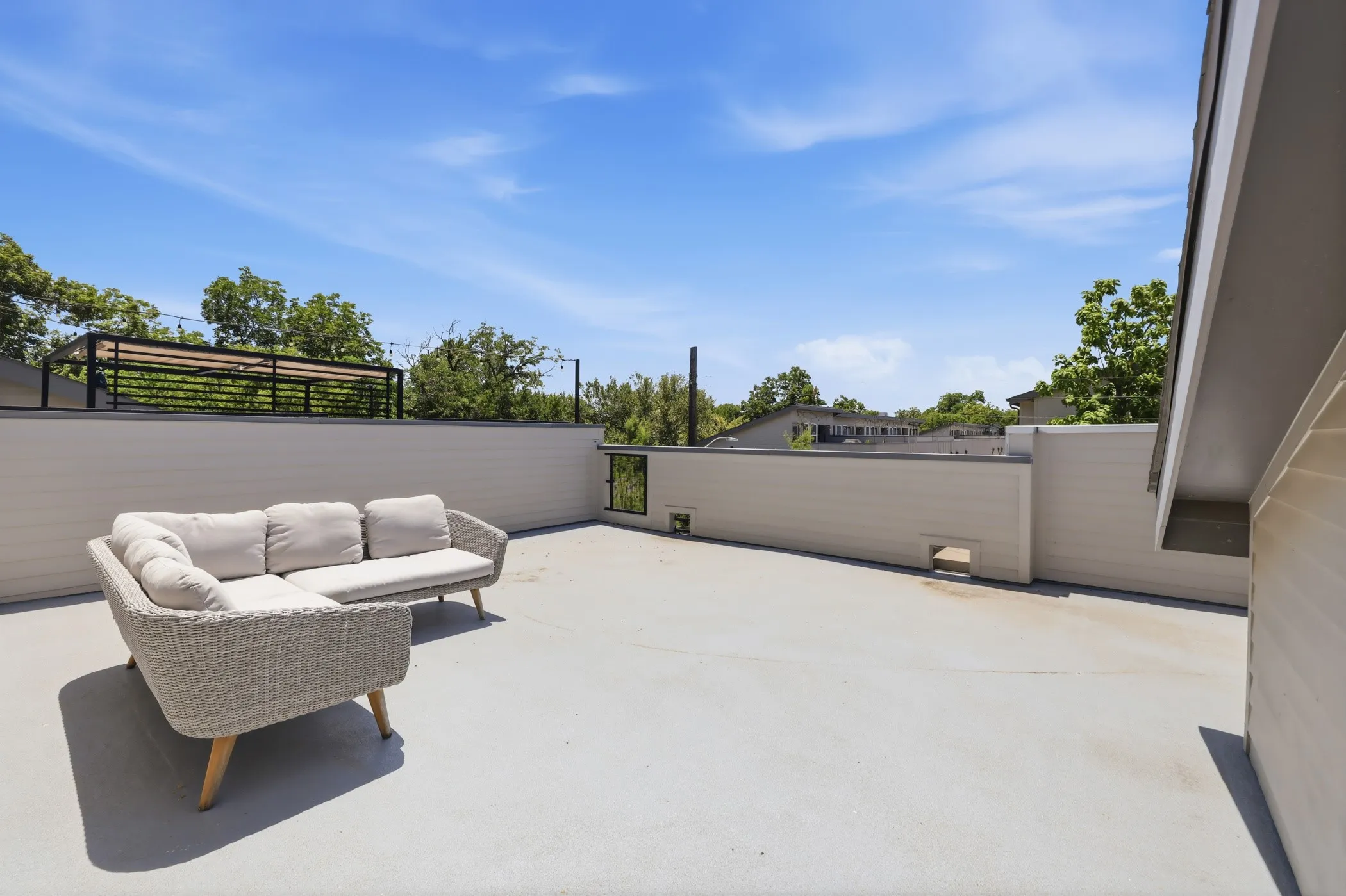 Expansive rooftop deck with high privacy walls and a built-in outdoor structure featuring black metal railing