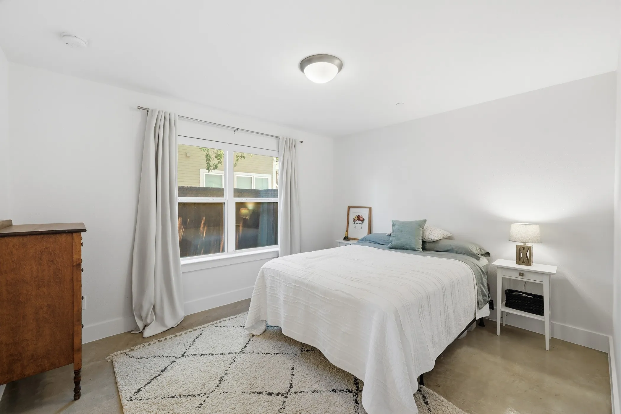 White walls, concrete flooring, and a large window with white trim