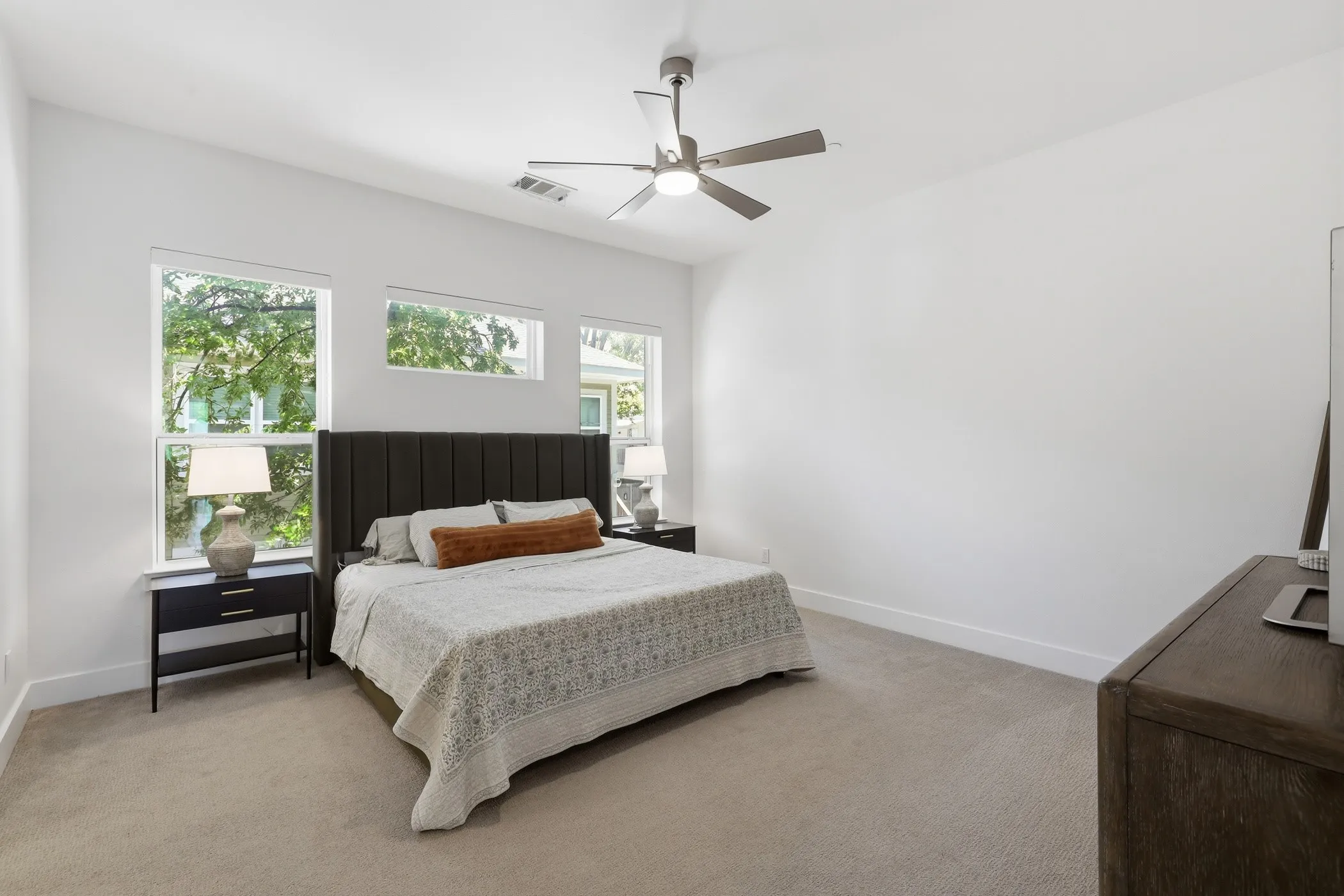 Carpeted bedroom with a vaulted ceiling, ceiling fan, and multiple windows