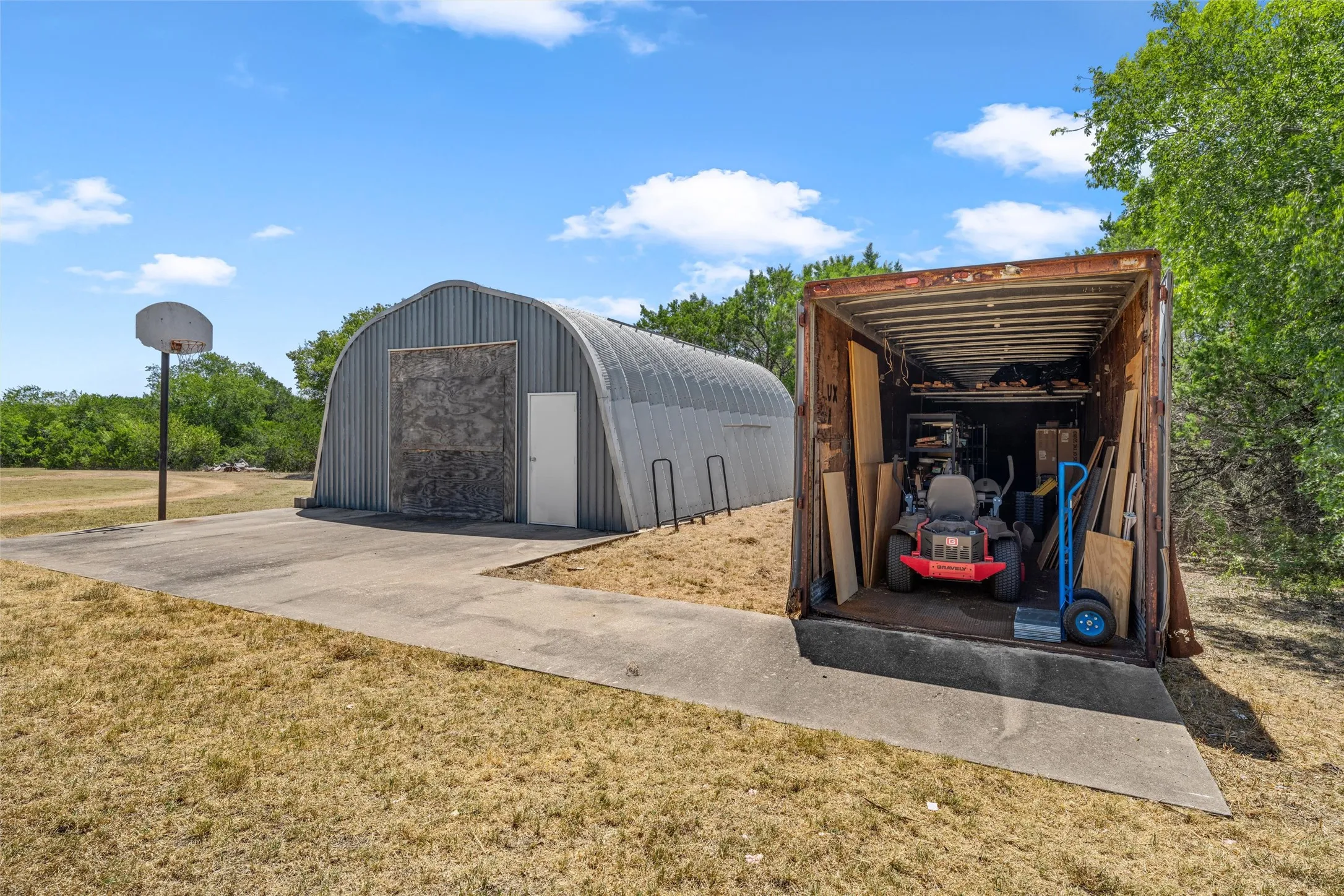 Quonset hut-style structure, concrete slab, and storage container
