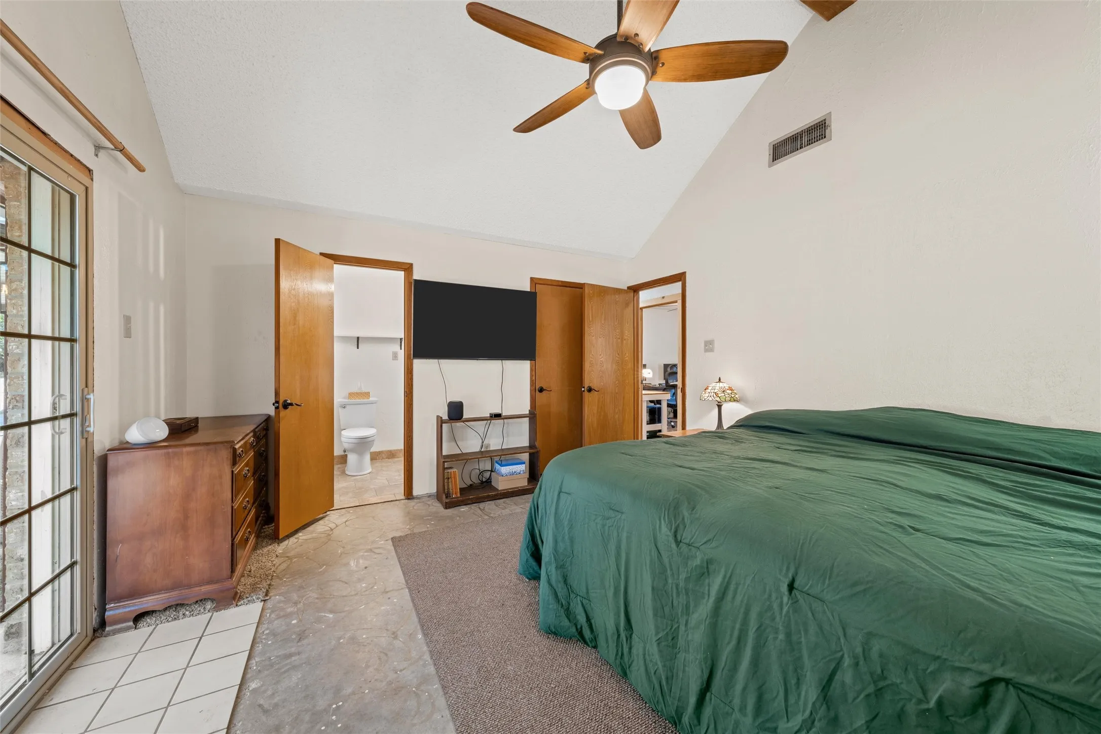 Vaulted ceiling with a wood-finish ceiling fan, wood-paneled doors, and a glass-paneled exterior door