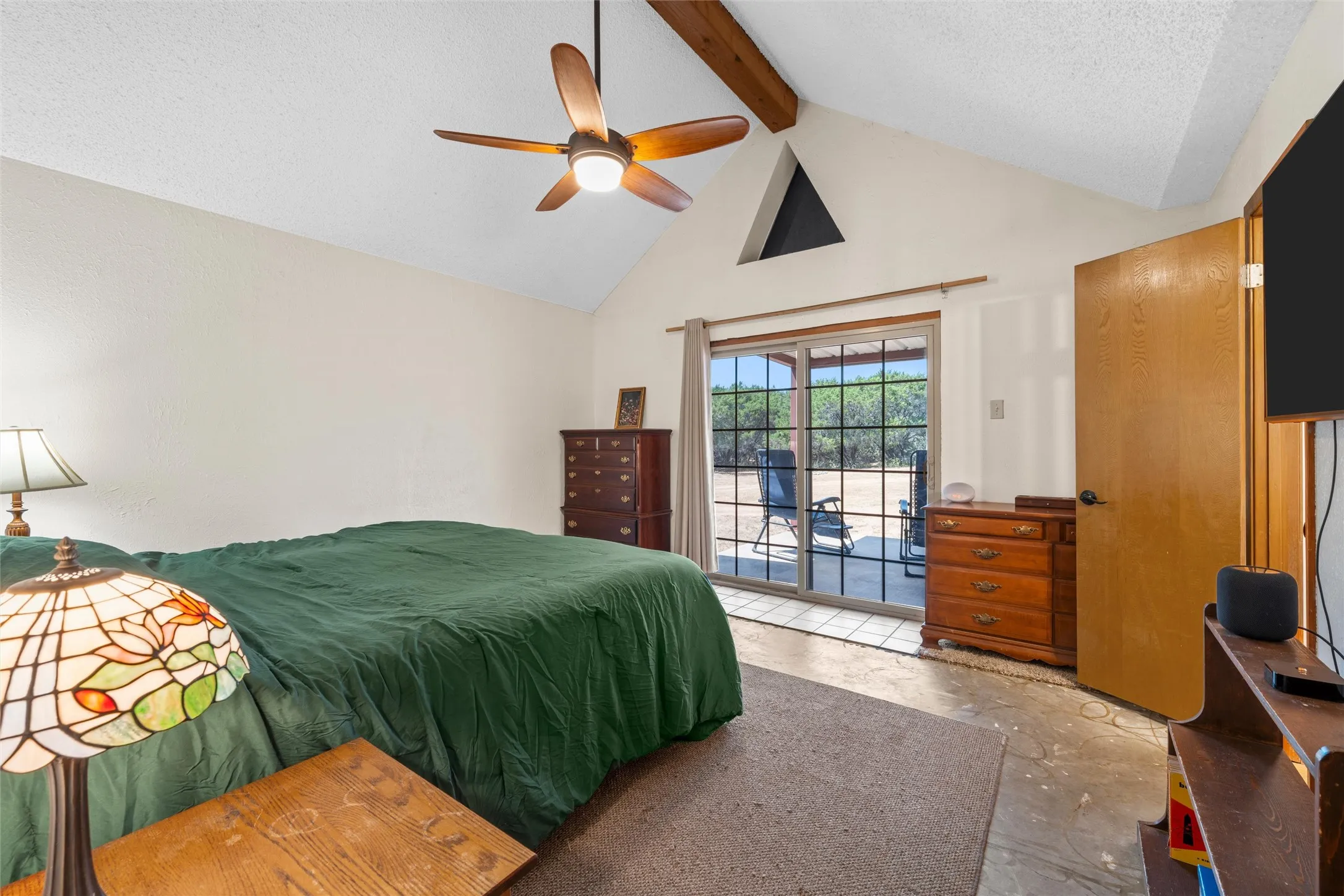 Vaulted ceiling with exposed wood beams, ceiling fan, and triangular accent window