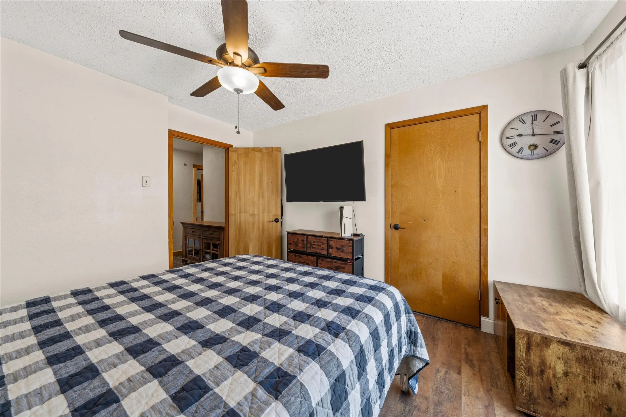 Wood-finish flooring with a ceiling fan light fixture and light-toned wall paint
