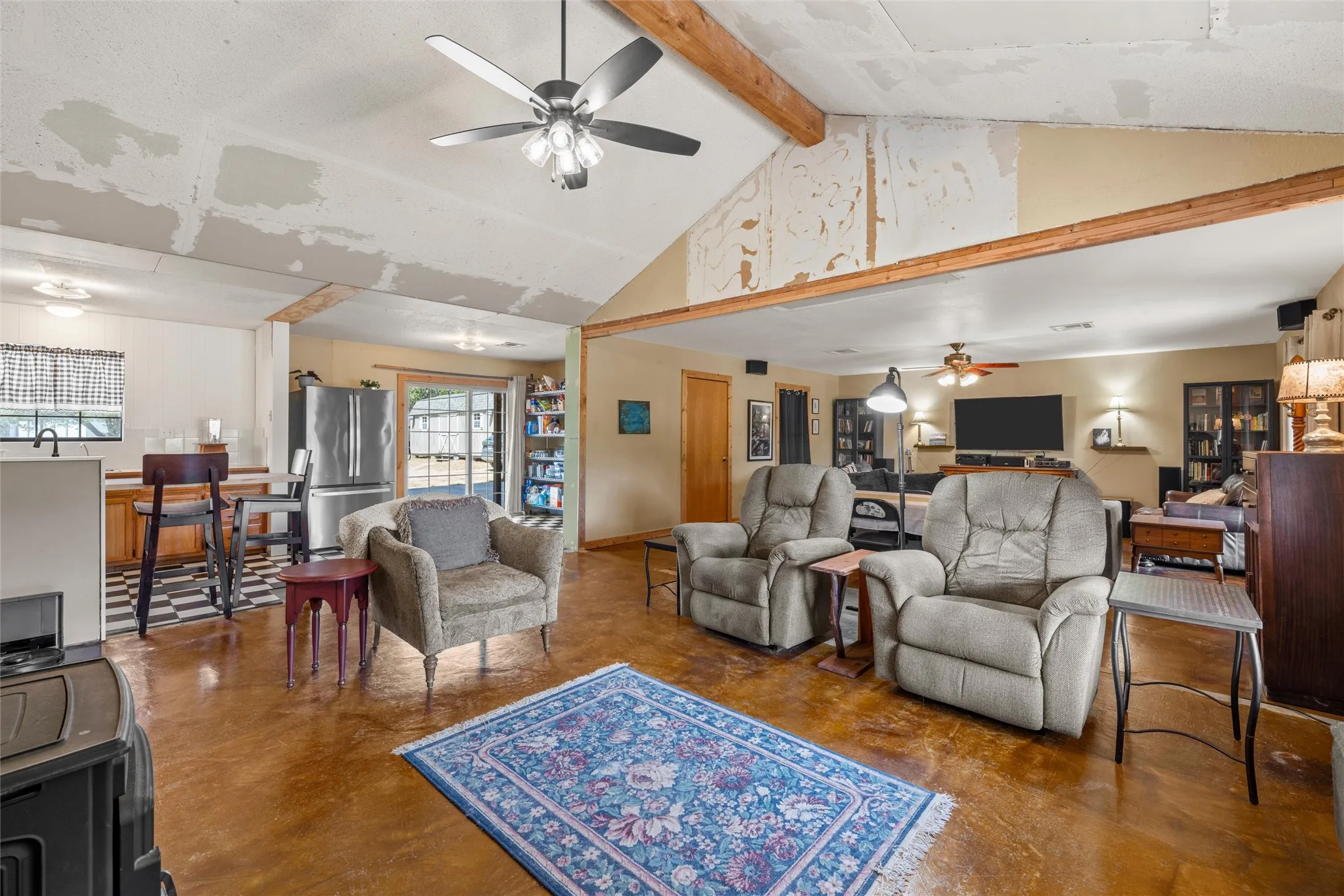 Vaulted ceiling with exposed wood beams, wood-finish flooring, built-in cabinetry, ceiling fans, and a sliding glass door