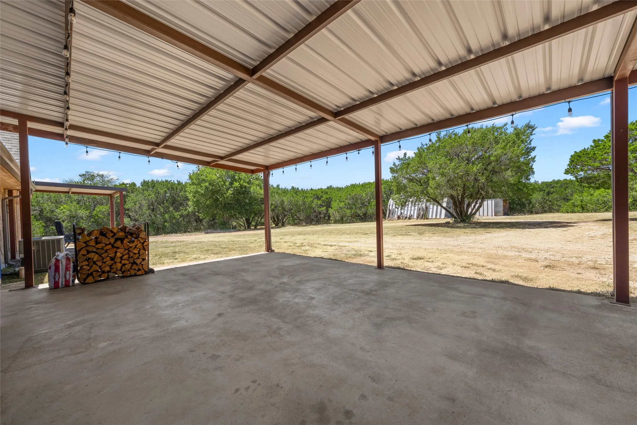 Expansive covered patio featuring a concrete surface, metal roofing, and string lighting