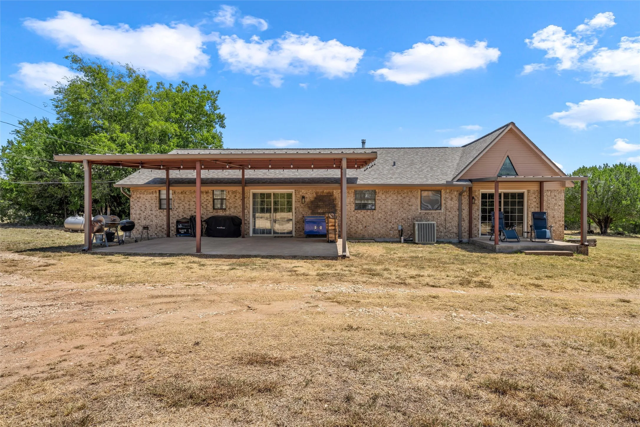 Brick exterior with a gabled roofline, extended covered patio, and a separate covered deck